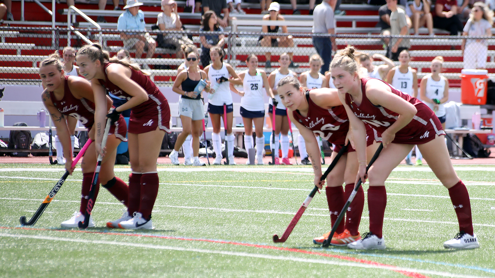 four field hockey players in red uniforms lining up on the circle for an offensive penalty corner