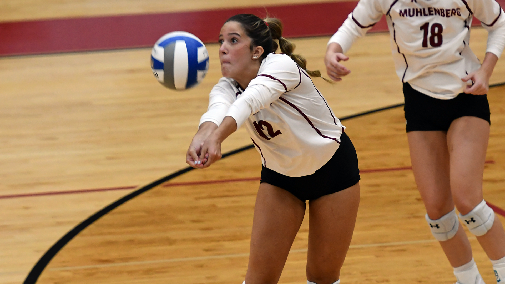 a volleyball player in a white jersey digging the ball