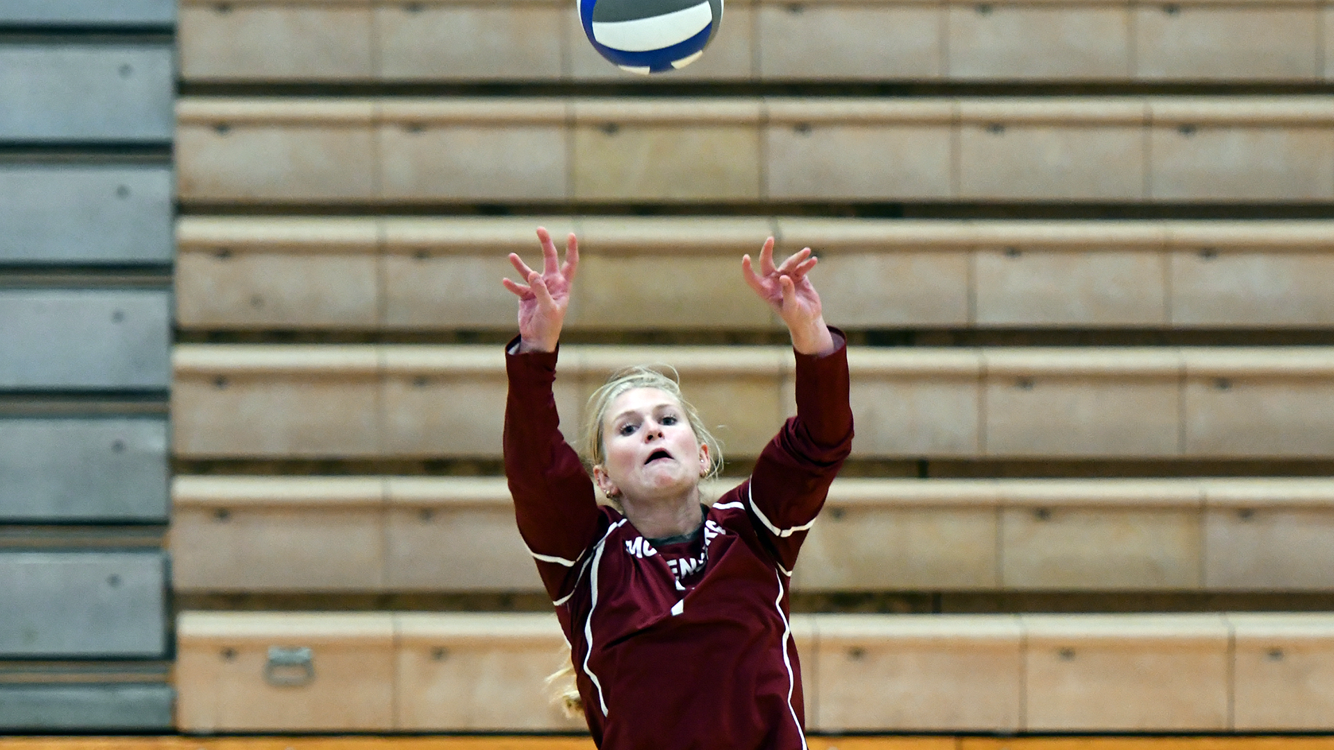 a volleyball player in a red jersey setting the ball indoors