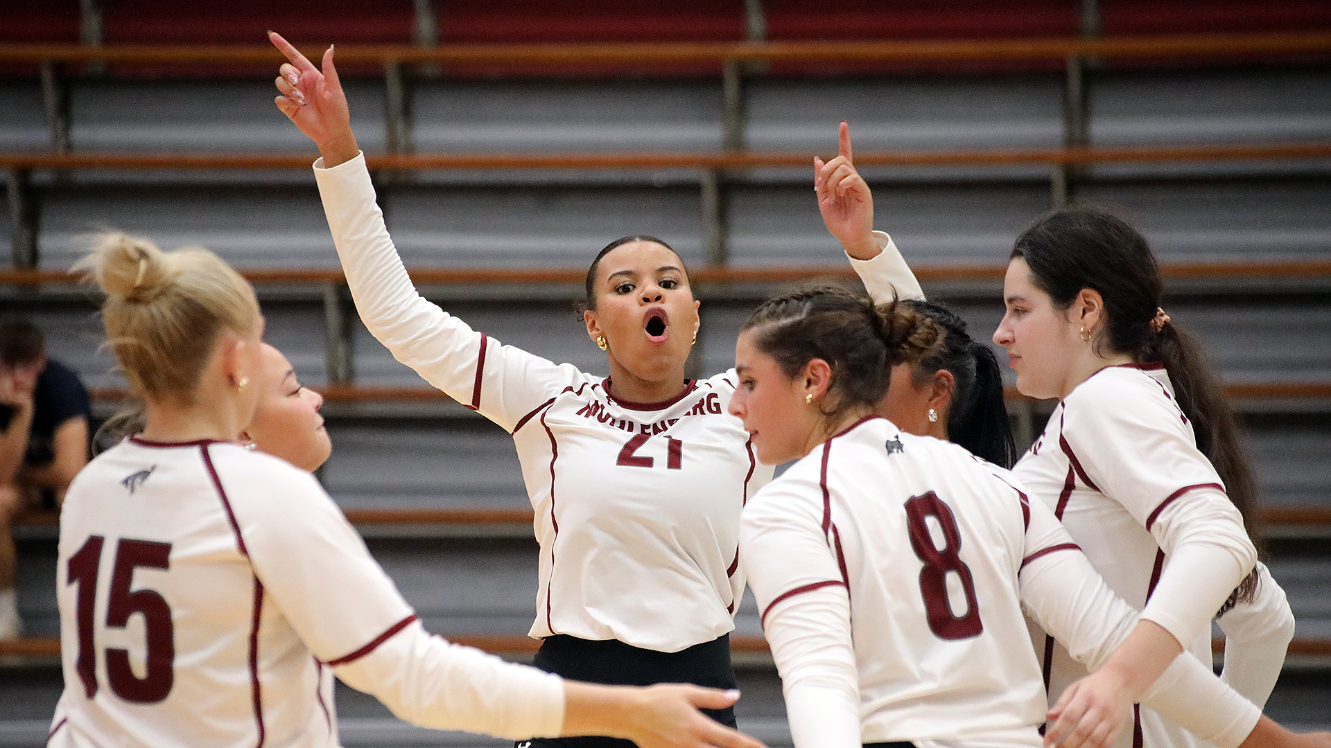 volleyball players in white uniforms celebrate a point