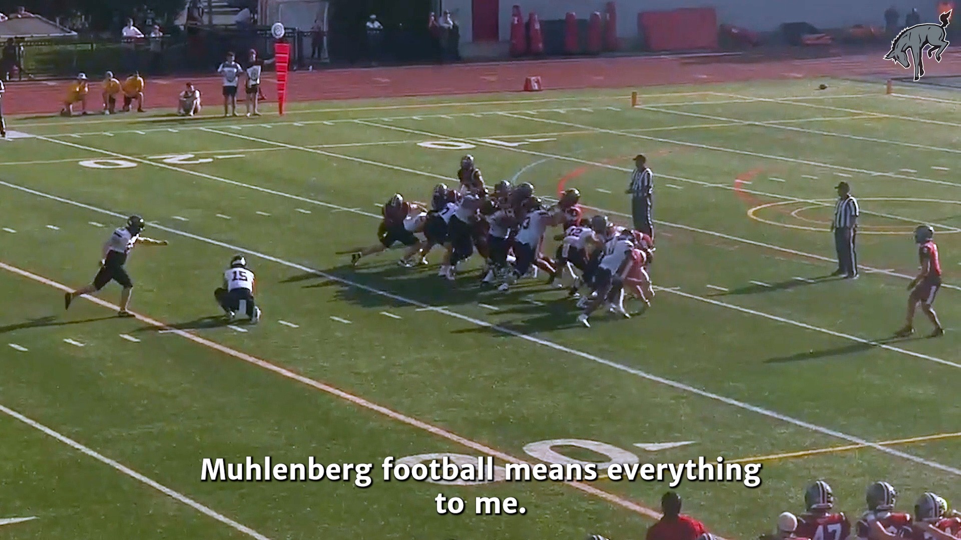 wide photo of a team in white uniforms attempting a field goal on a green turf field while a team in red uniforms defense