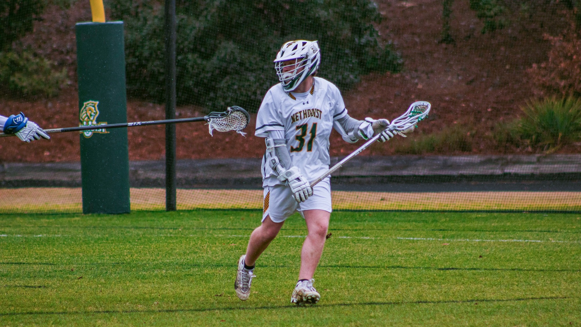 Logan Garrett with the ball and a defender with his stick out toward him