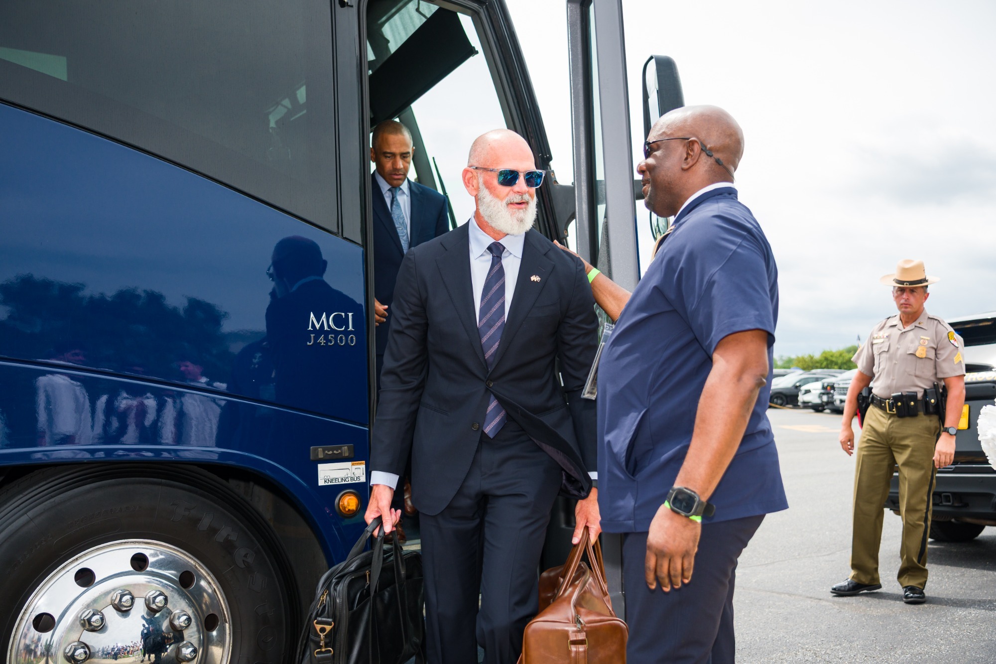 Navy head football coach Brian Newberry is greeted by NCIS agent Chris Coles as he gets off the bus