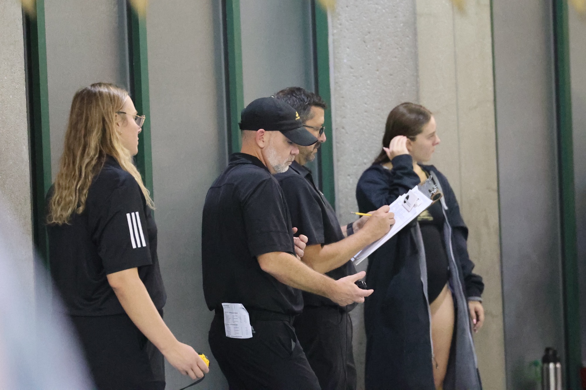 Kyle Hunt and assistant coaches look at watches to track time