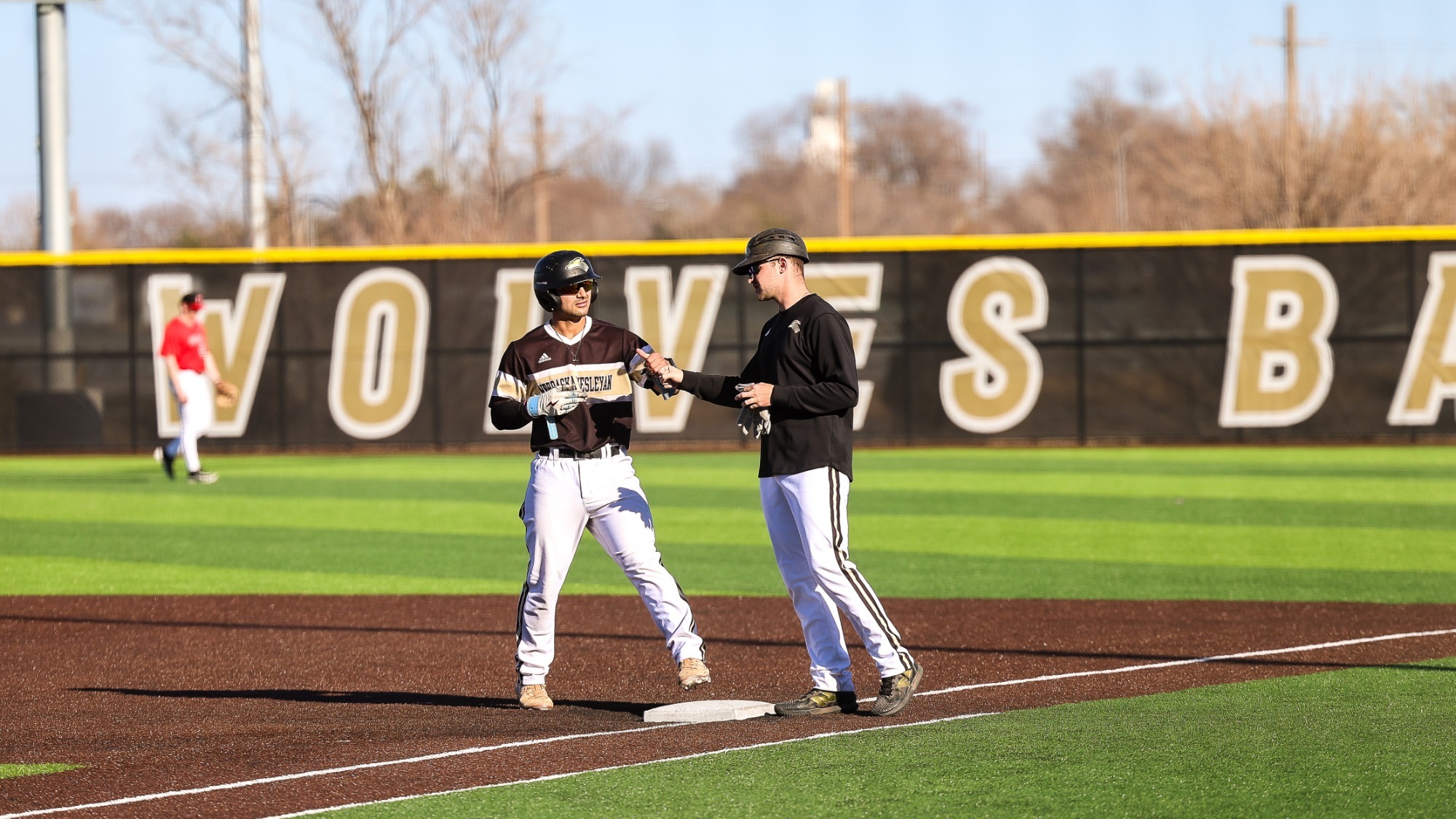 Duncan Ortega & Coach Bennett fist bump after Ortega reaches base on a single.