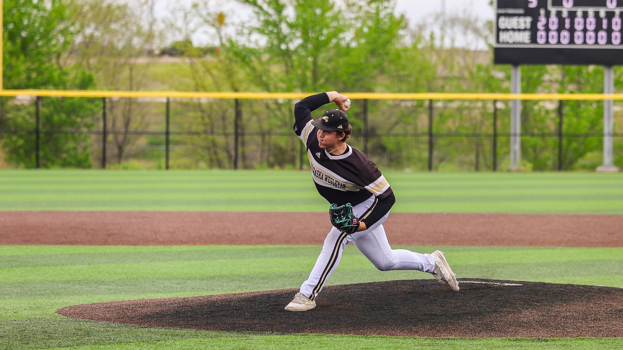 Caleb DeWitt fires in a pitch with his arm bent back.