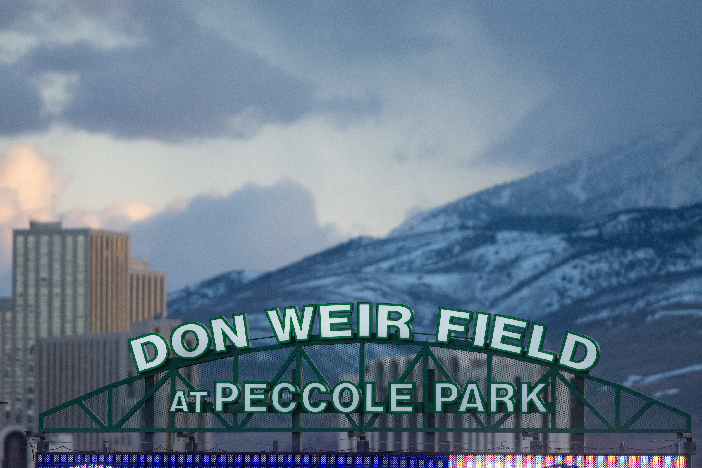 A close up of the Don Weir Field at Peccole Park sign with the mountains in the back.