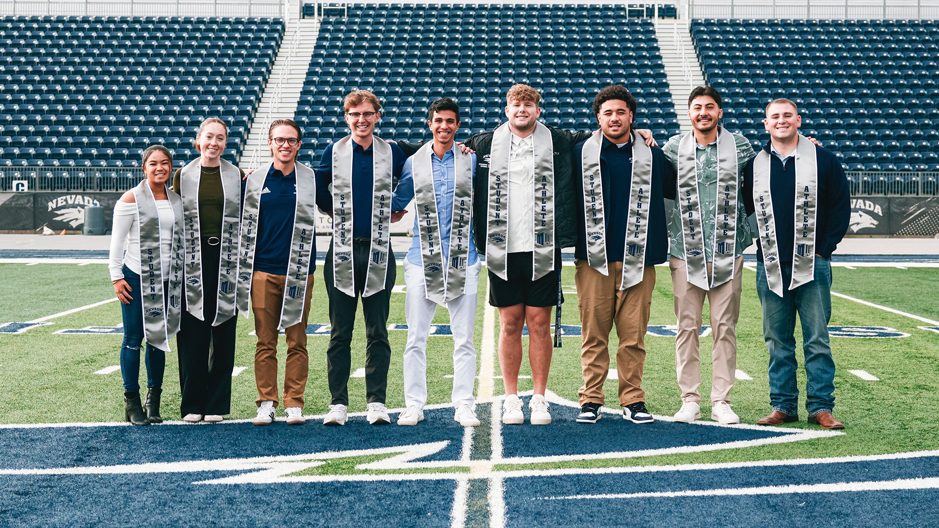 Photo of Nevada student-athlete graduates standing on Chris Ault Field