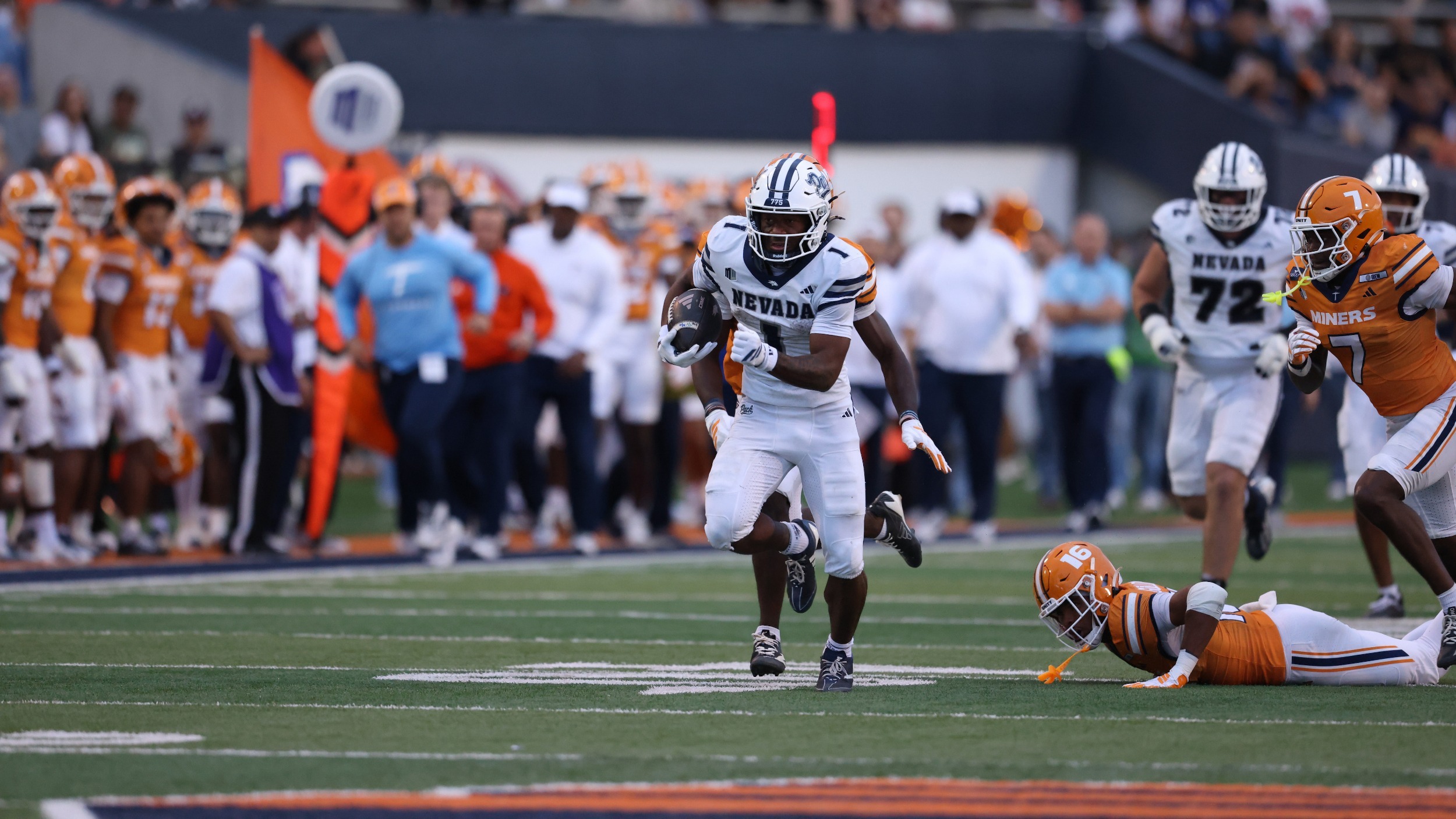 Herschel Turner in white jersey and pants runs away from UTEP defenders