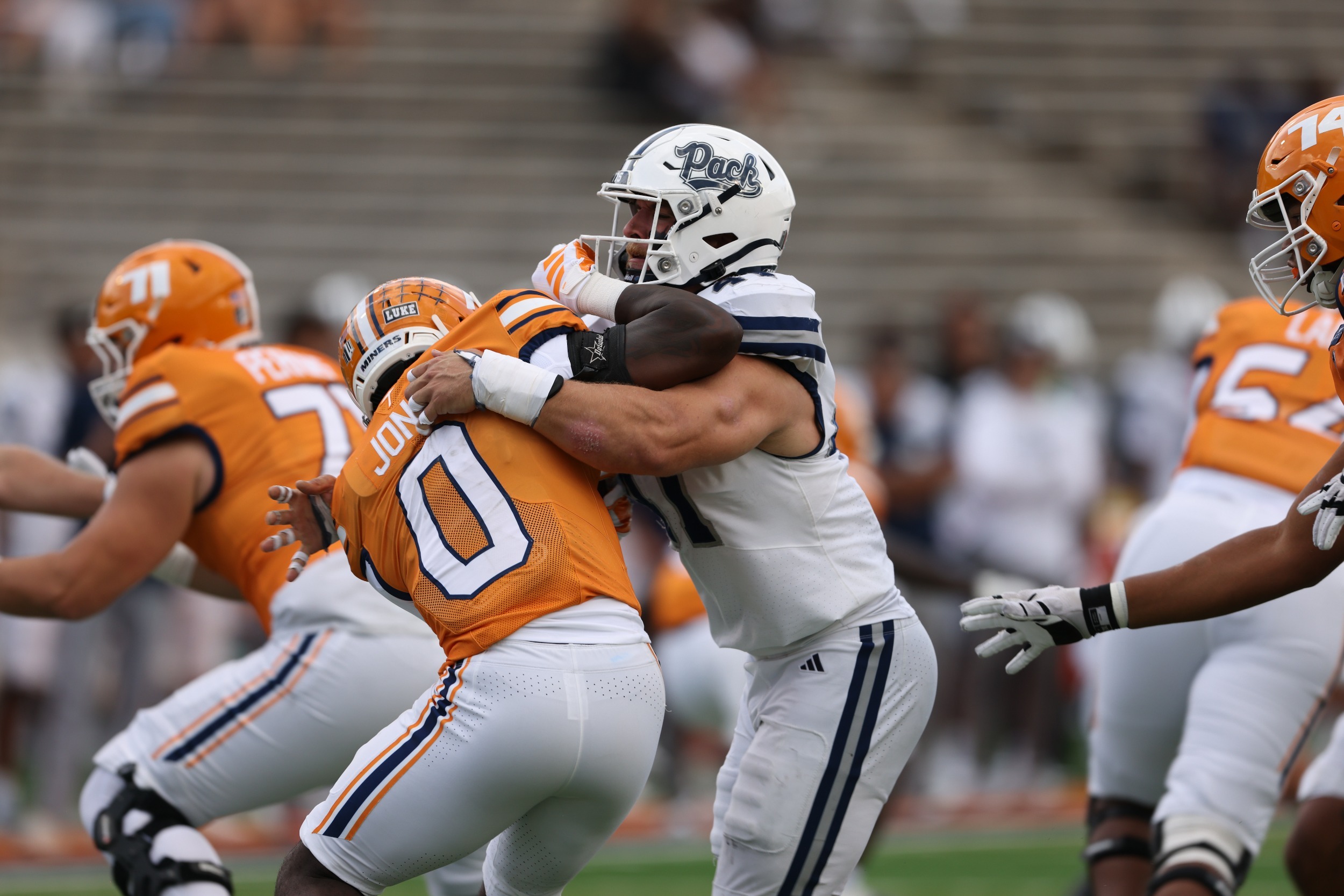 Dylan LaBarbera in white uniform shoving with a player in an orange uniform
