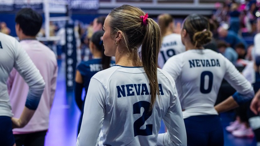 A volleyball player in a light-colored shirt from behind with a dark numeral two
