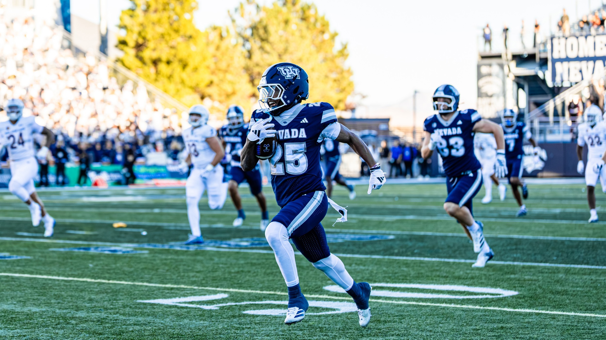 A Nevada player in a dark uniform runs with the football