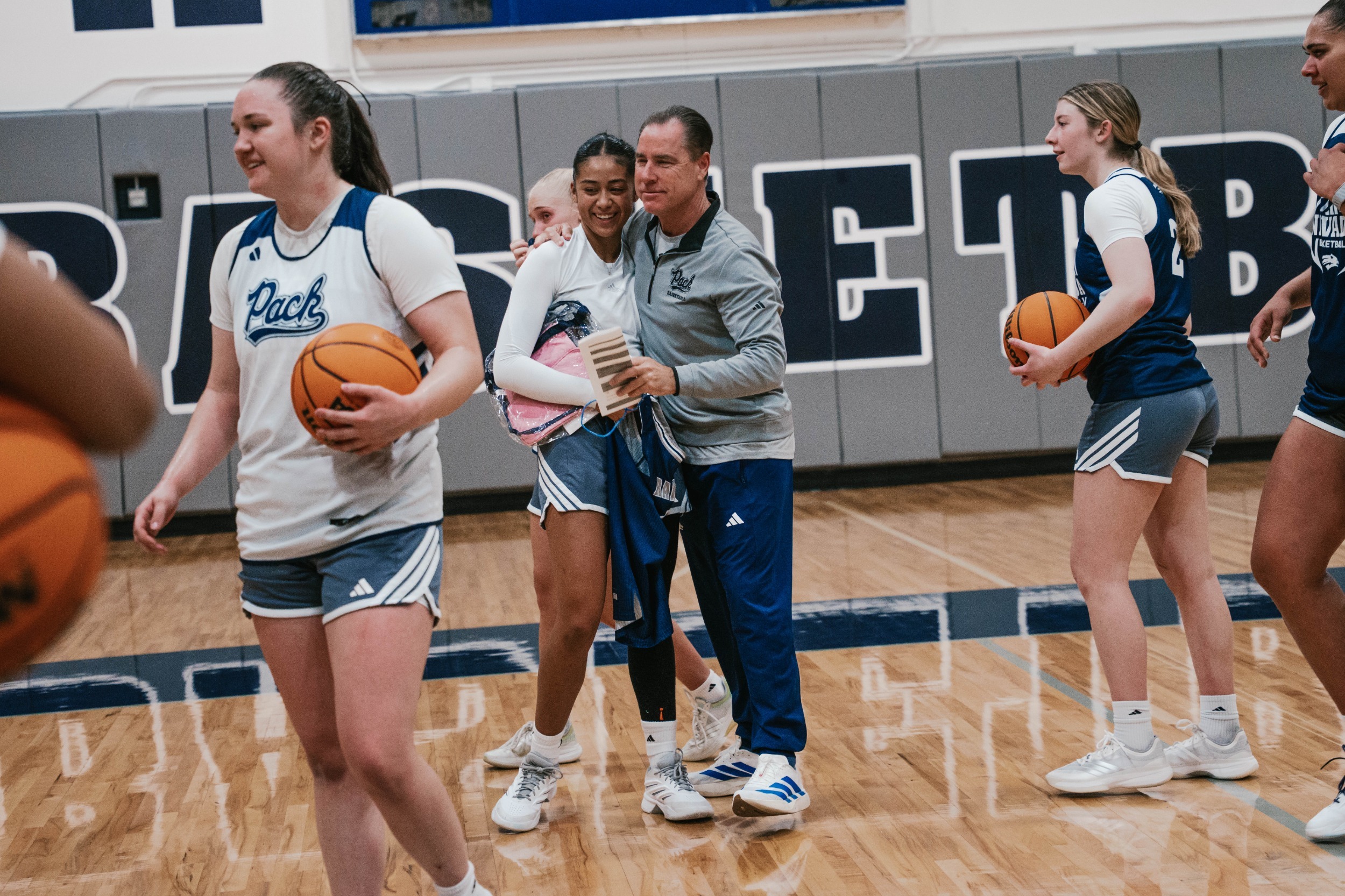 A female basketball player hugs her head coach after recieving an award