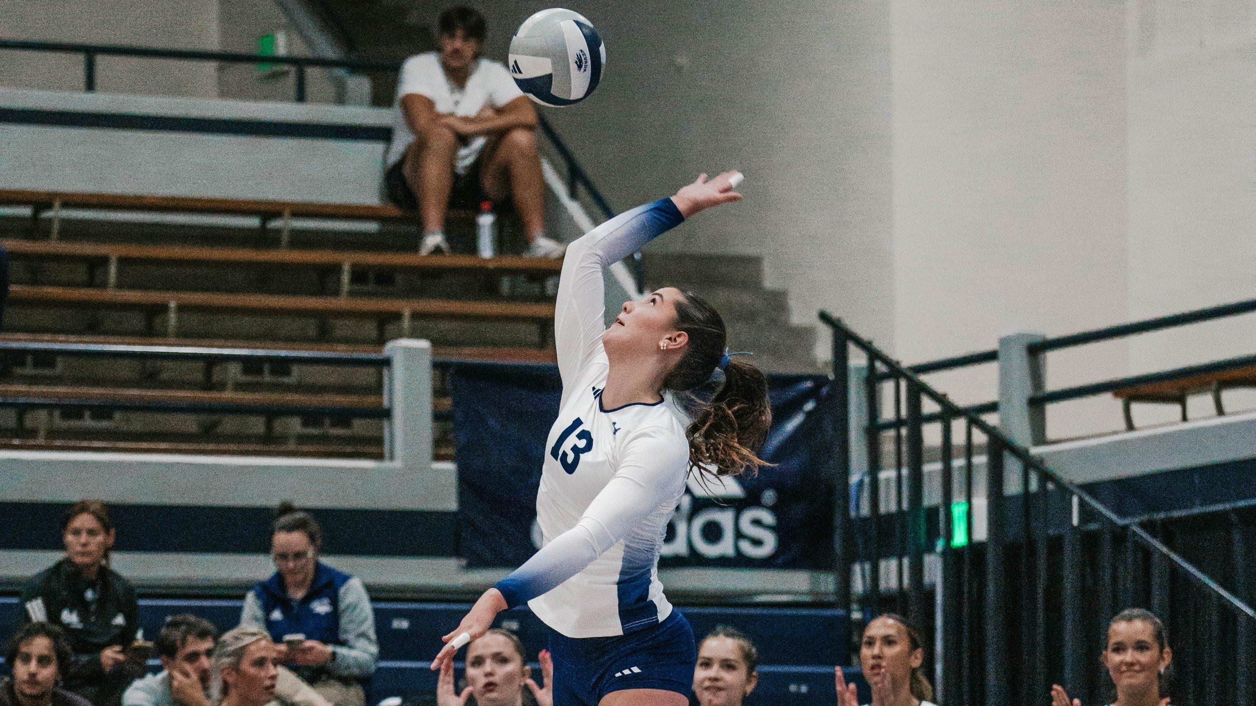 Nevada player in a light-colored shirt about to serve a volleyball