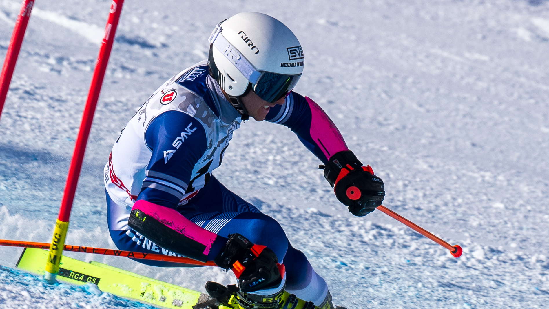 David Morken in a white helmet and ski suit makes a turn at a giant slalom gate
