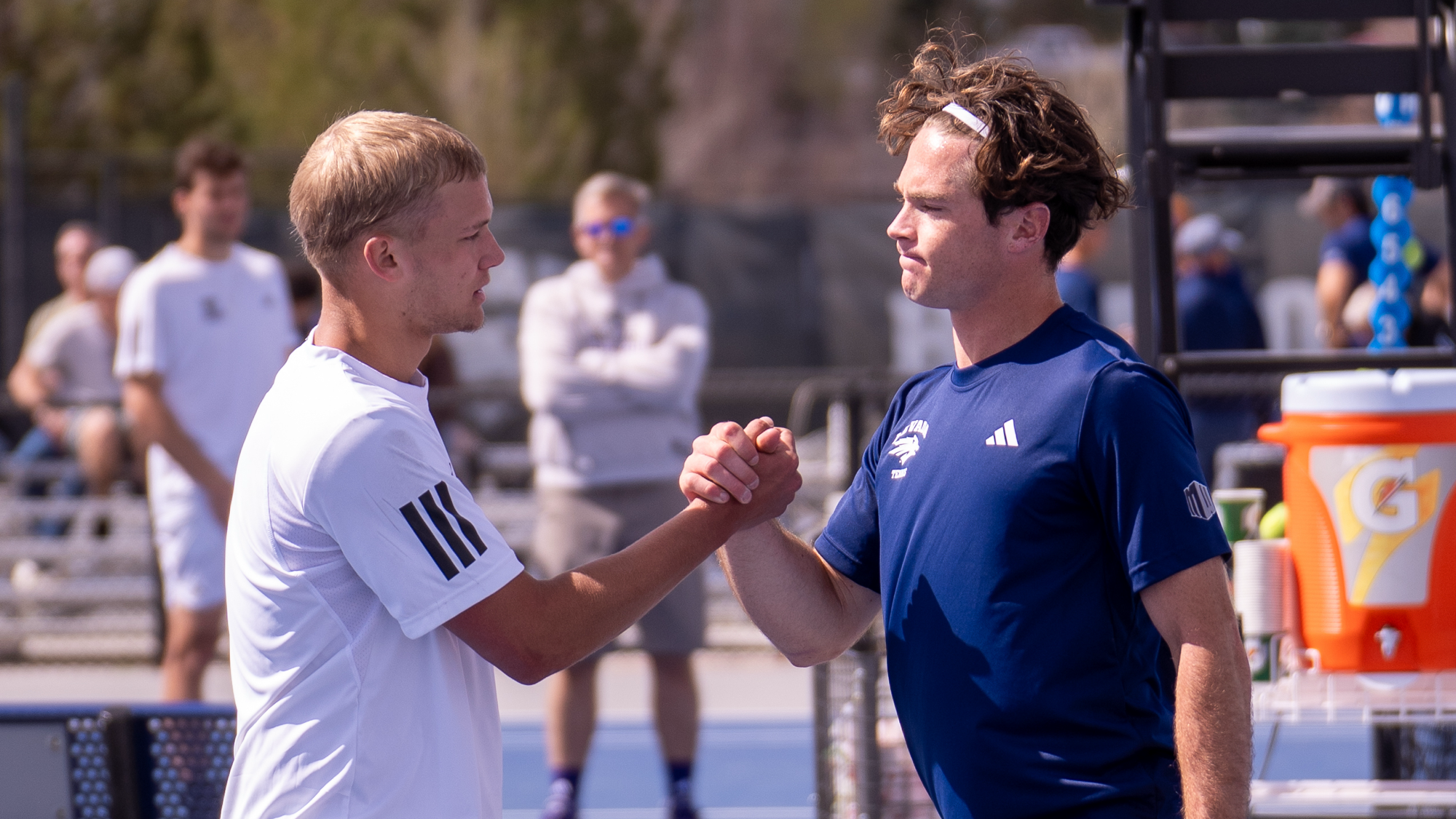 A Weber State and Nevada men's tennis players shake hands at the net after a match