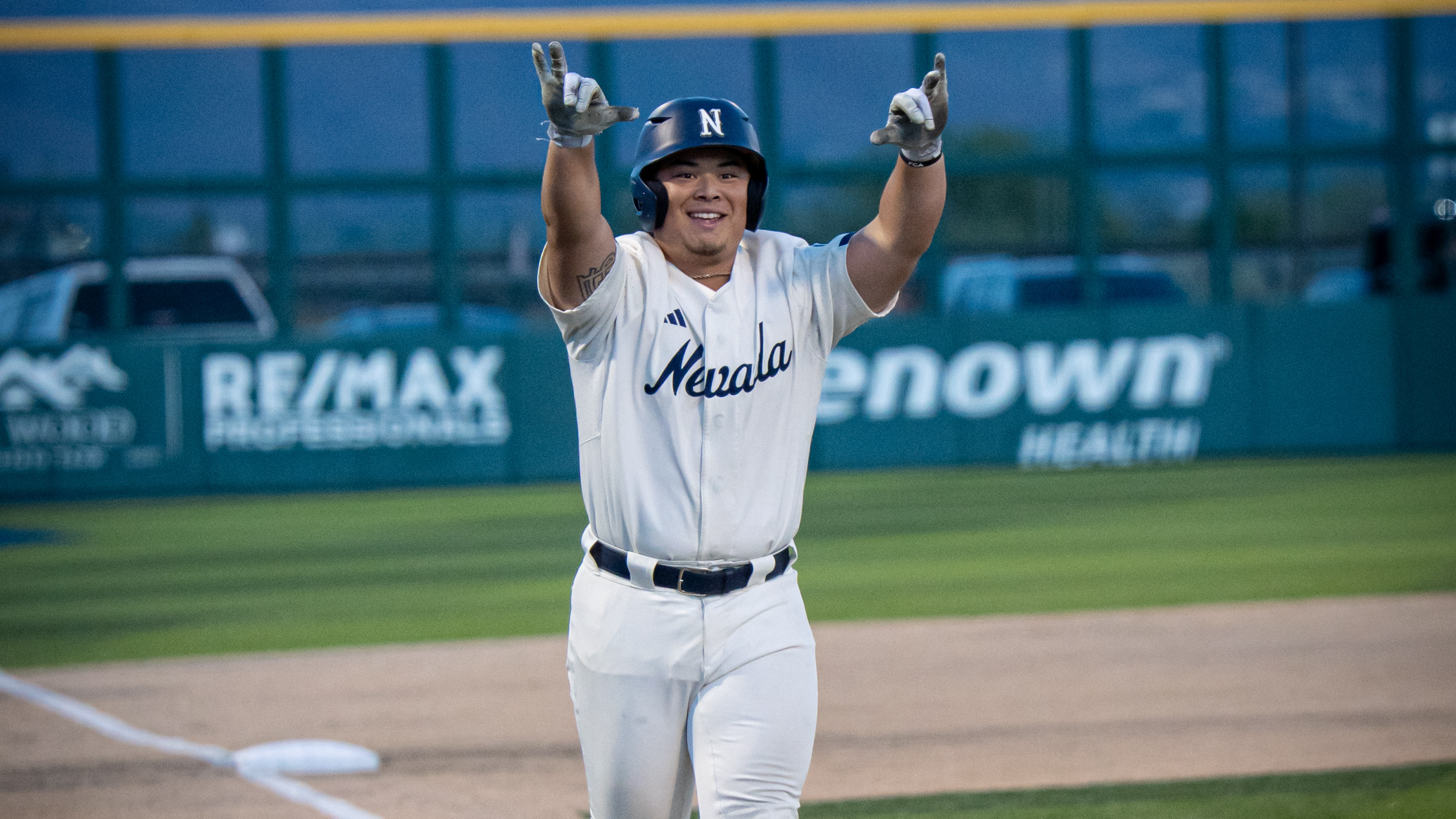 Sean Yamaguchi holding the Wolf Pack sign with each hand as he trots home on a home run