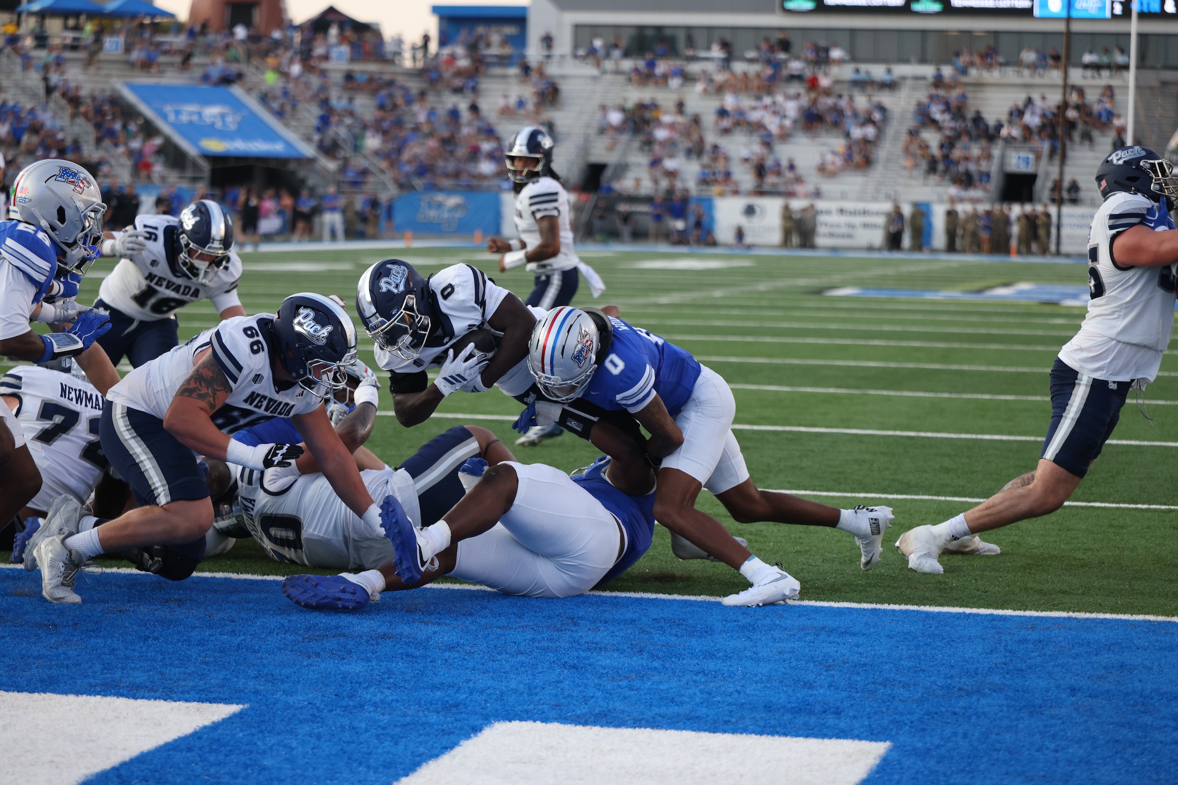 Wolf Pack player carrying the ball dives into the end zone