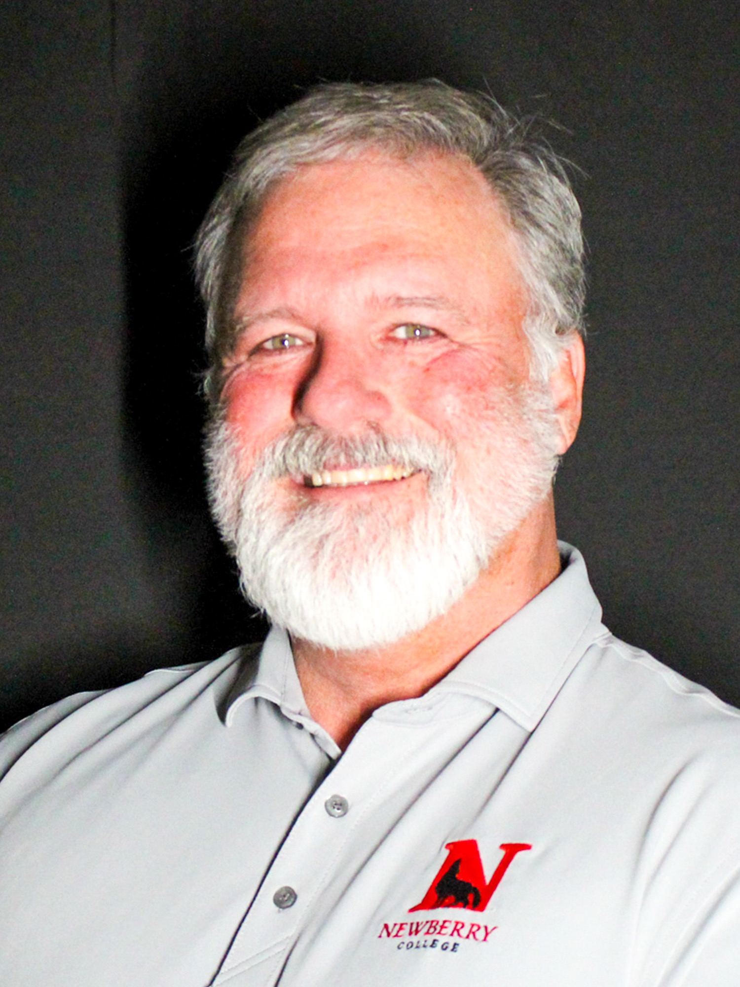 headshot of jimmy Stephens in a grey polo and black background