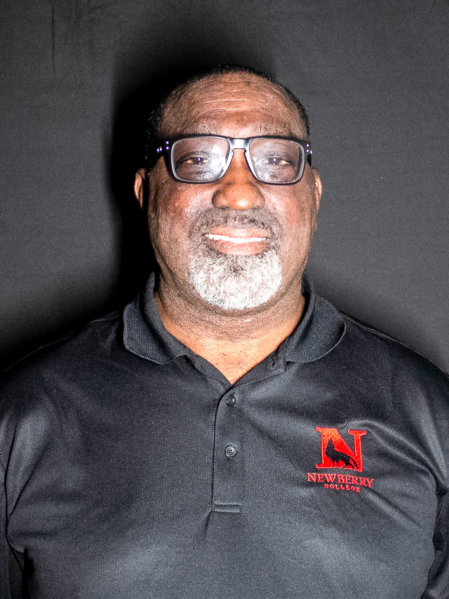 headshot of ulysses Sherman in a black polo and black background
