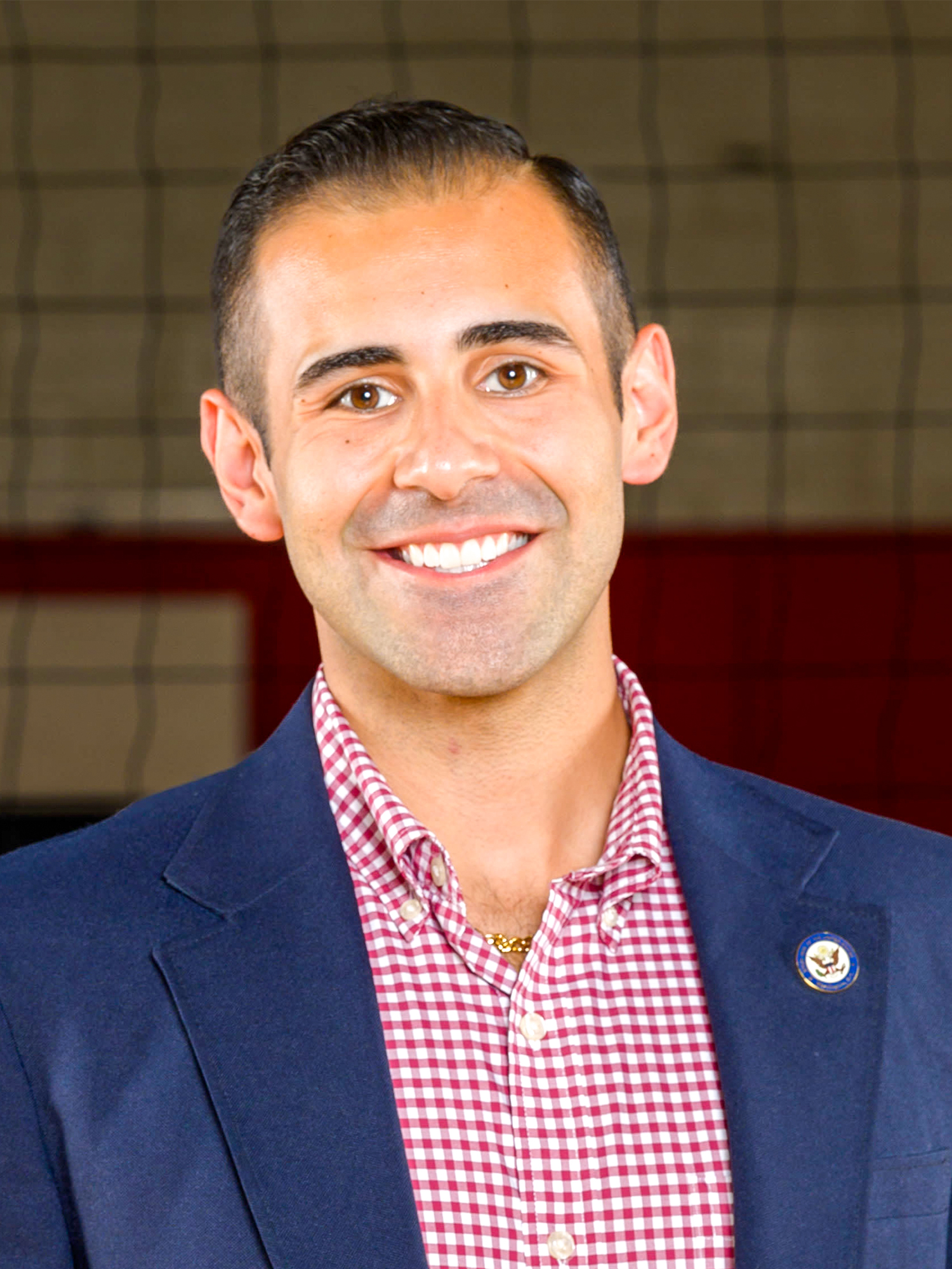 Headshot of assistant coach Justin Bass in a navy jacket with a red button up