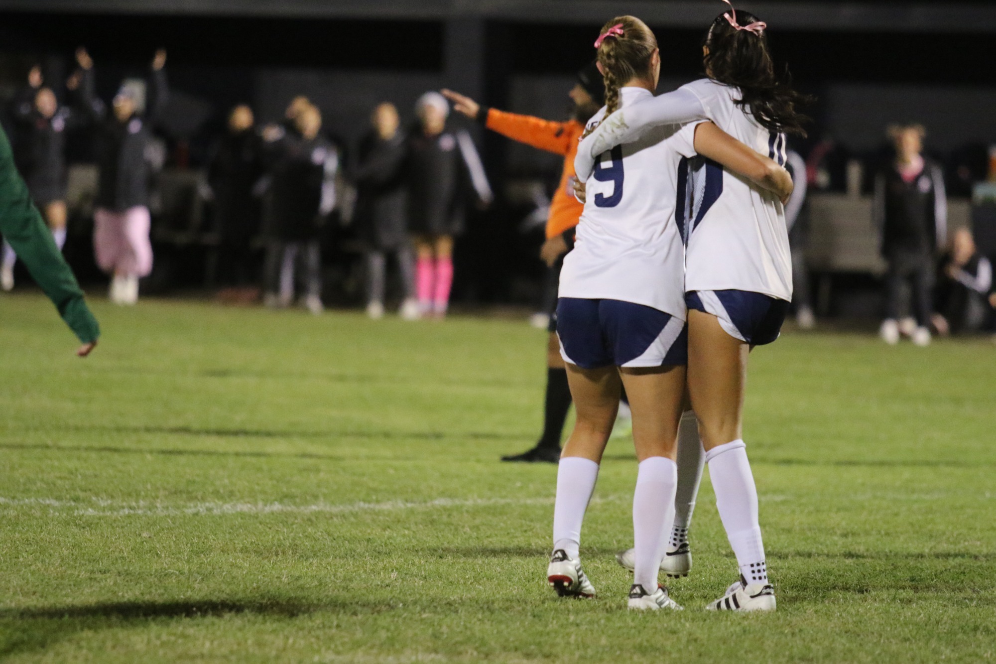 Two Newman players celebrate and hug after a goal