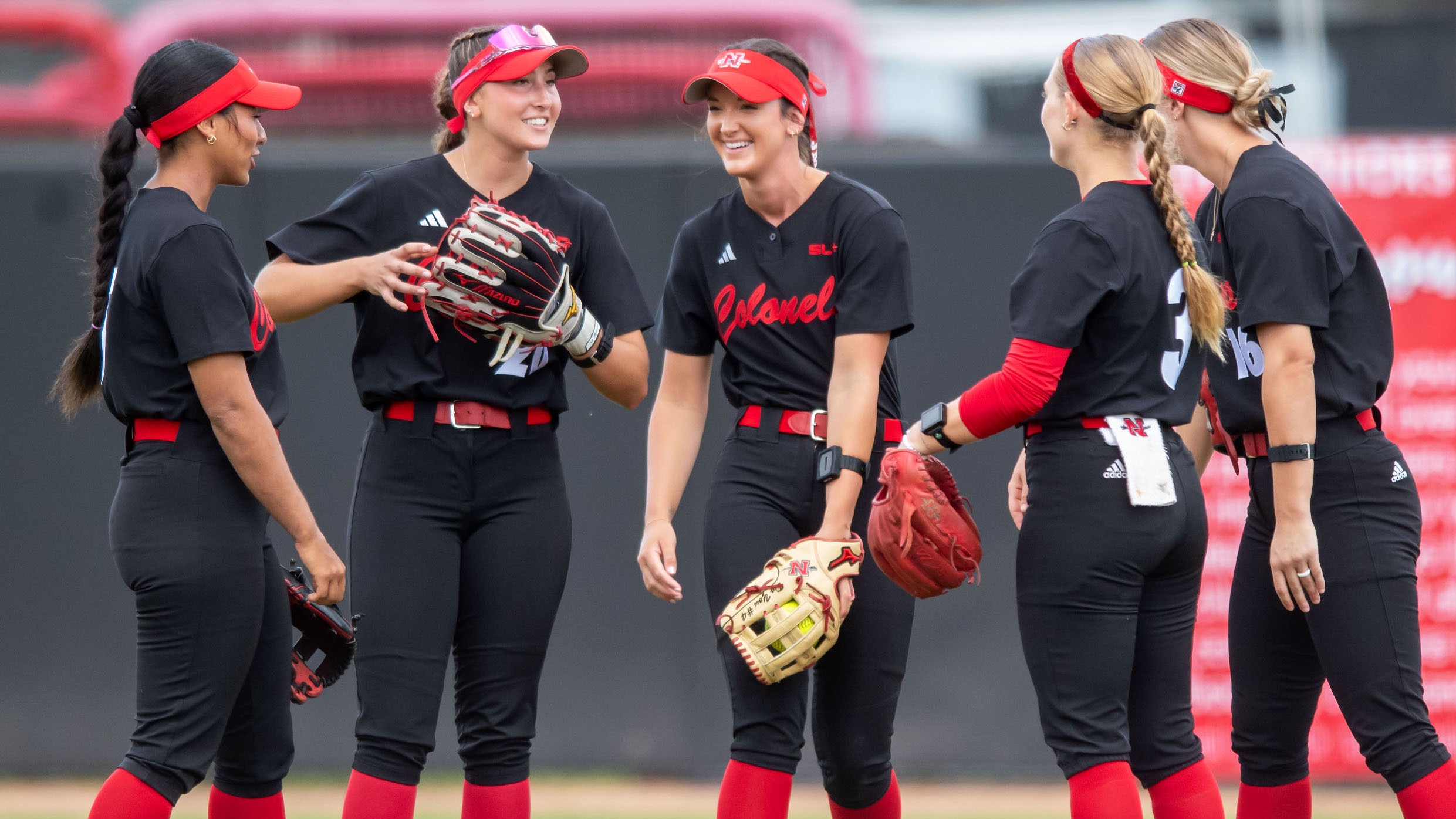Five Nicholls Softball players gather in the outfield