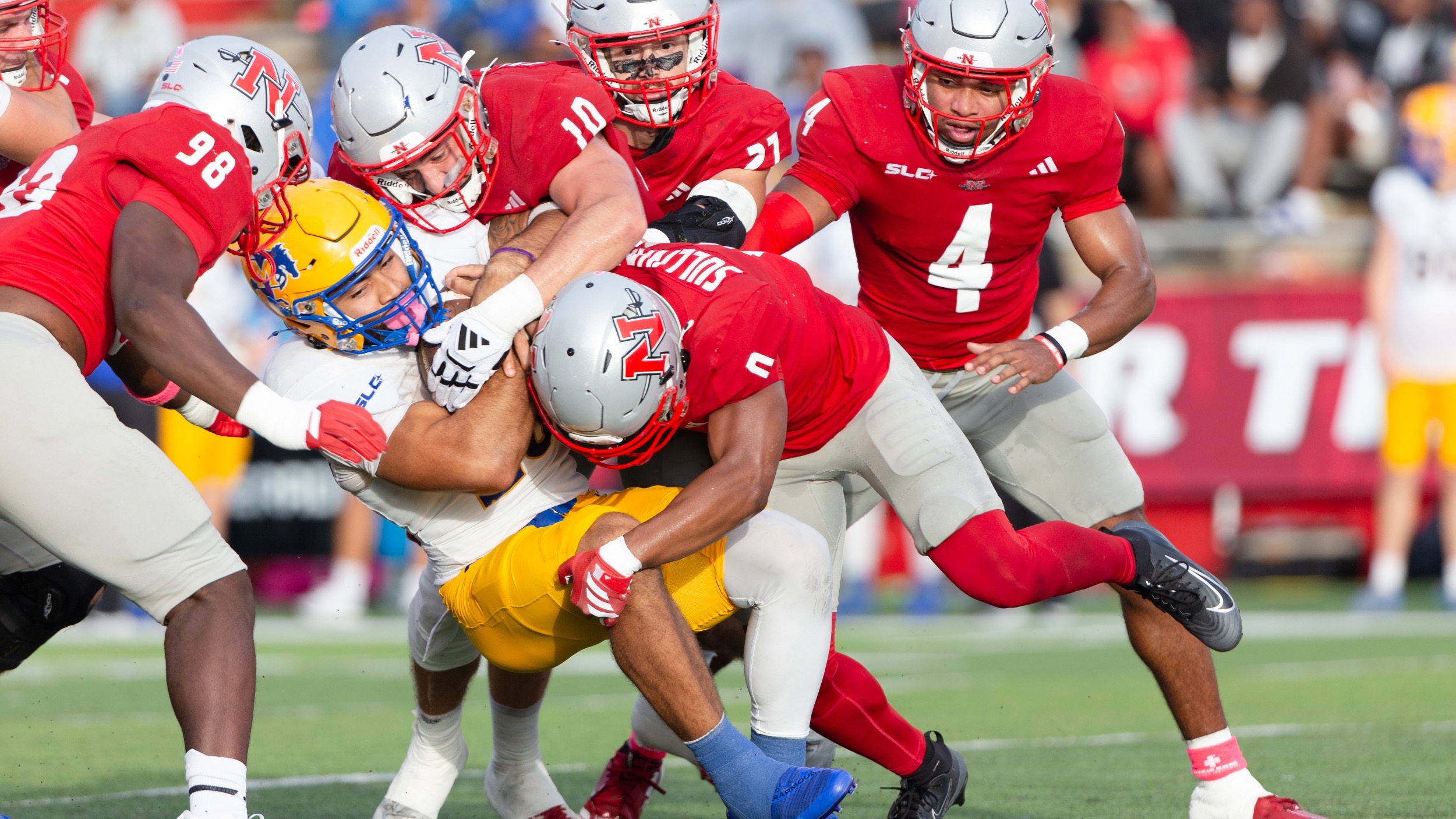 A group of Nicholls Football players makes a tackle against McNeese