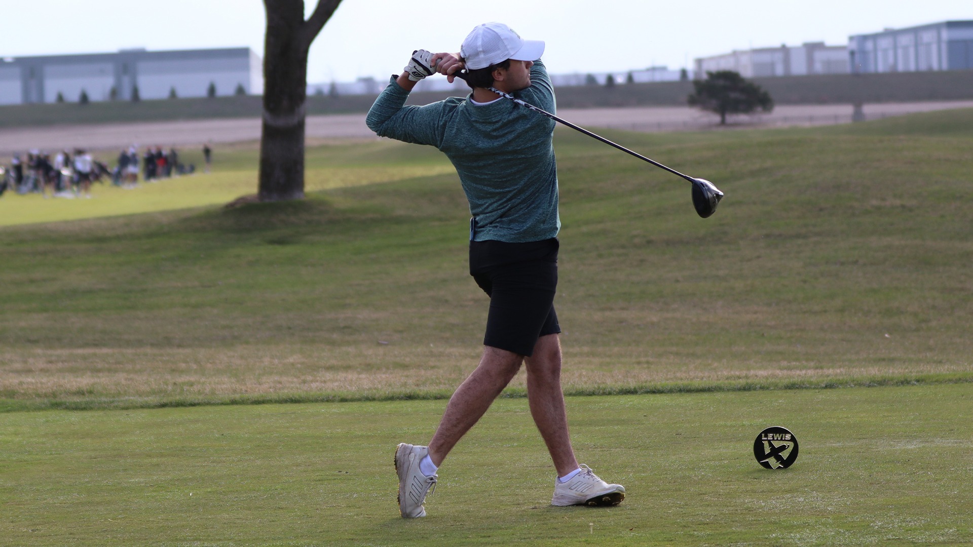 A side shot of a member of the men's golf team teeing off with his driver at the Flyer Spring Invite