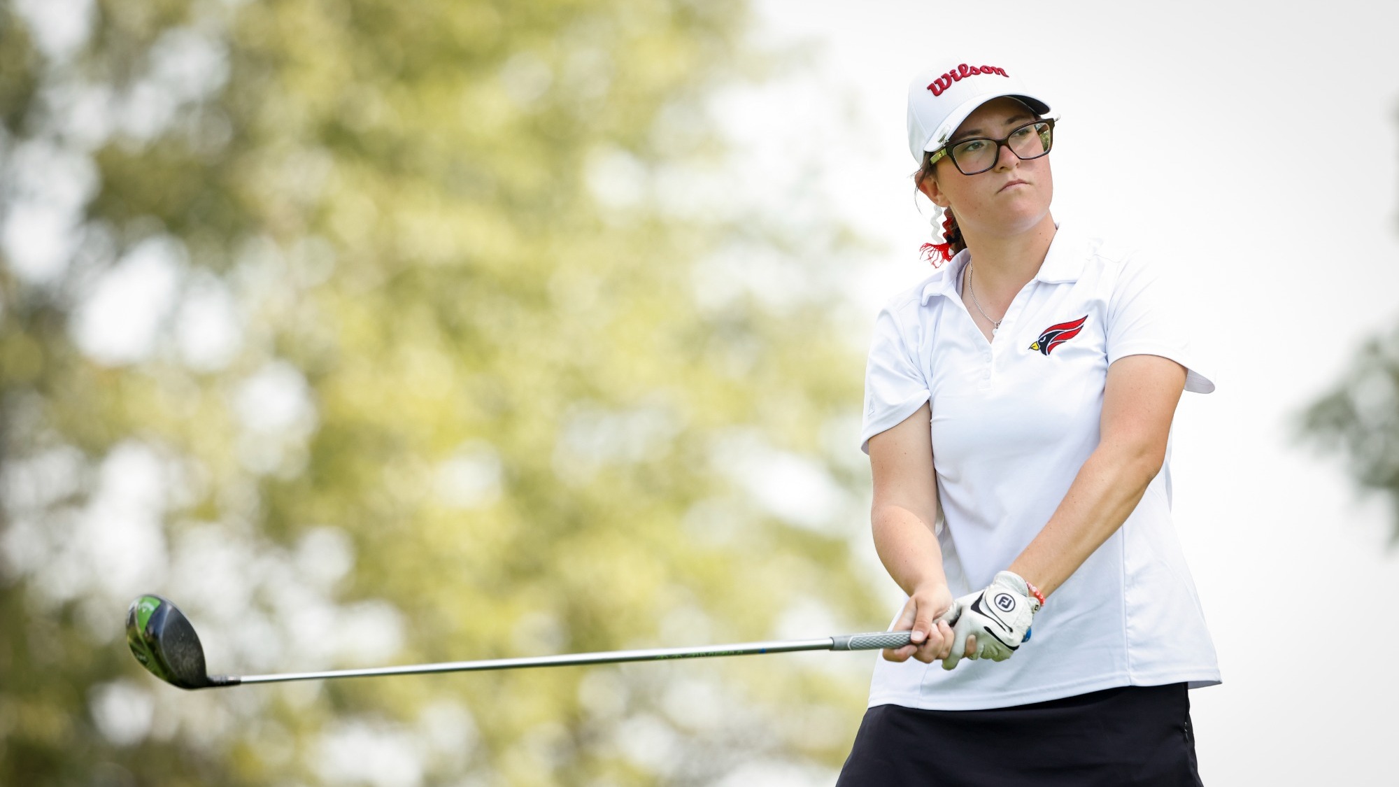 Women's golfer lines up her drive while extending her driver parallel to the ground. 
