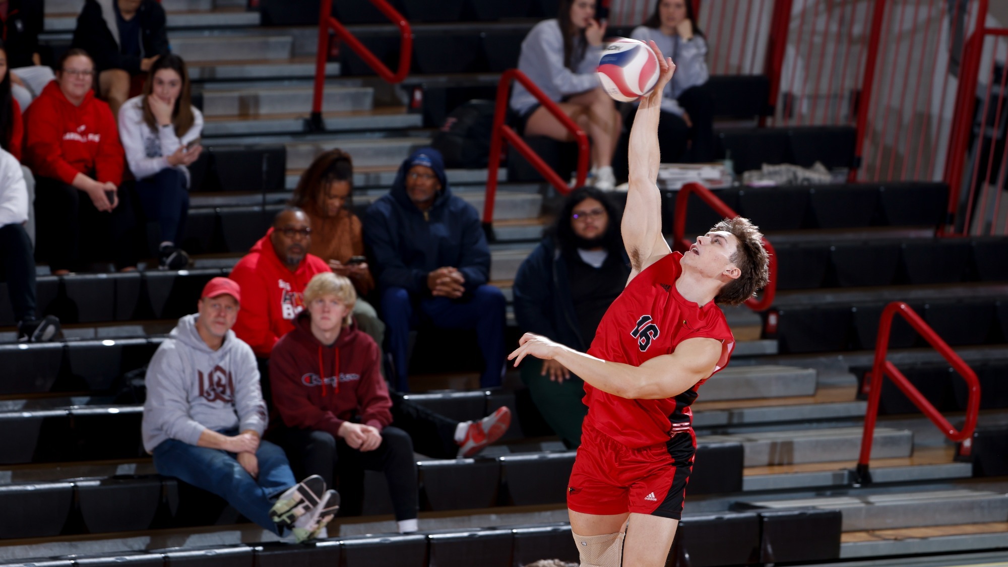 PJ Vaughan swings at the ball in midair to make a serve during a men's volleyball match