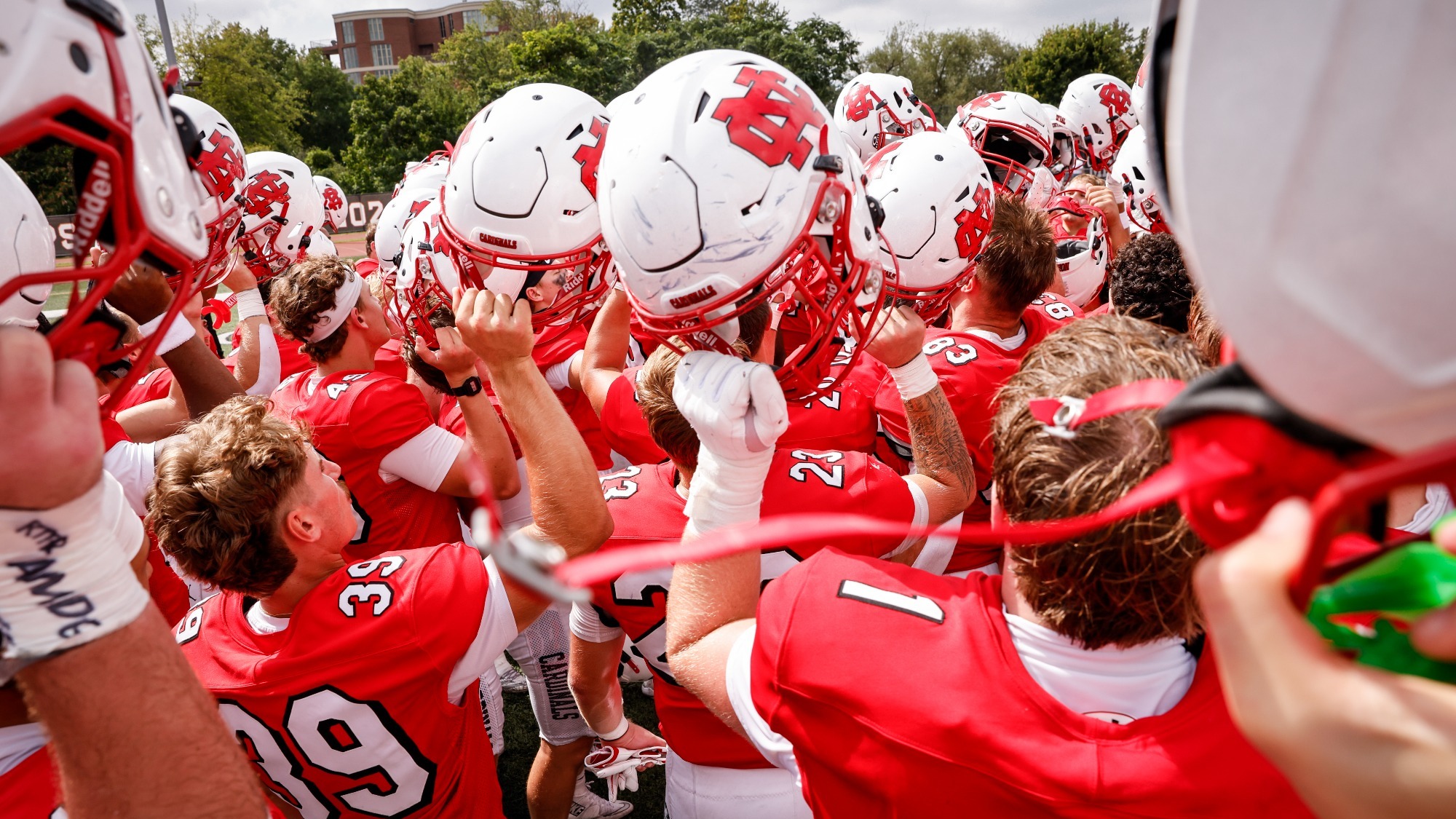 Football team in huddle raising helmets