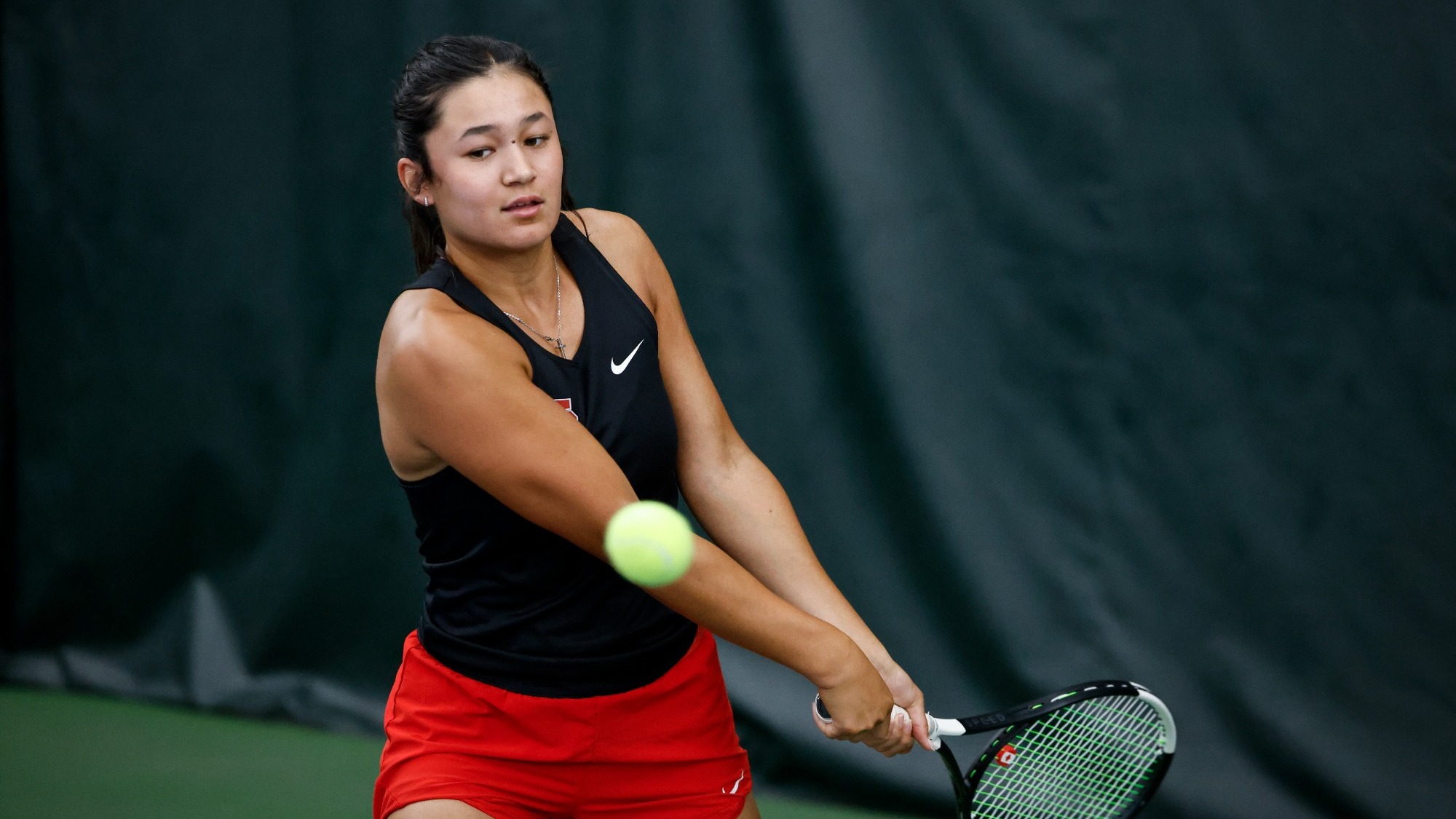 Berkley Klarich takes a backhanded swing while focusing intently on the ball.