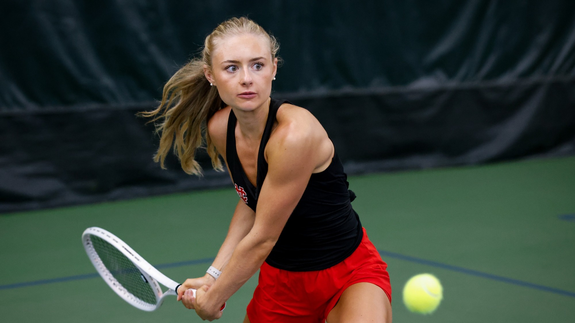 Alexandra Zaskowski winds up to take a backhanded swing during a tennis rally.
