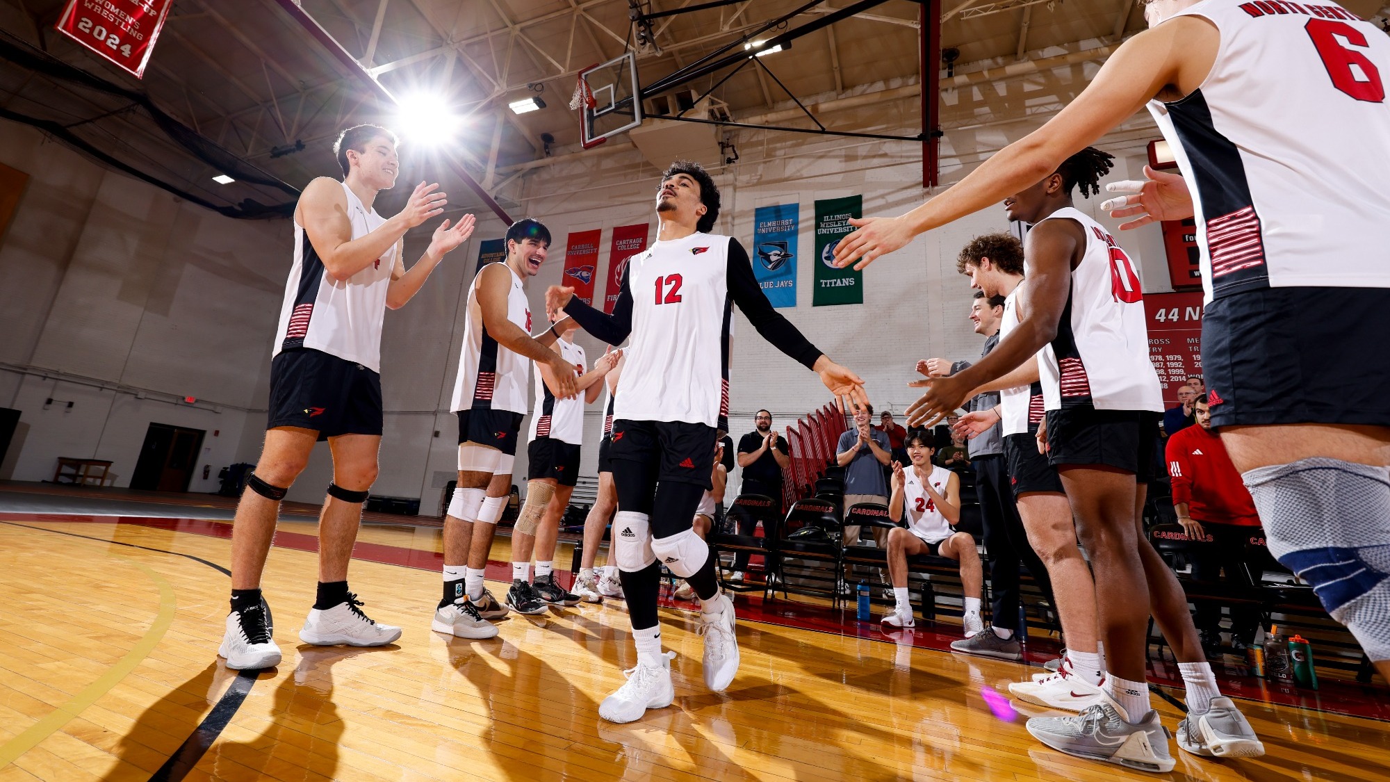 Jonathan Brown high fives teammates as he runs onto the court after having his name announced in the starting lineup.