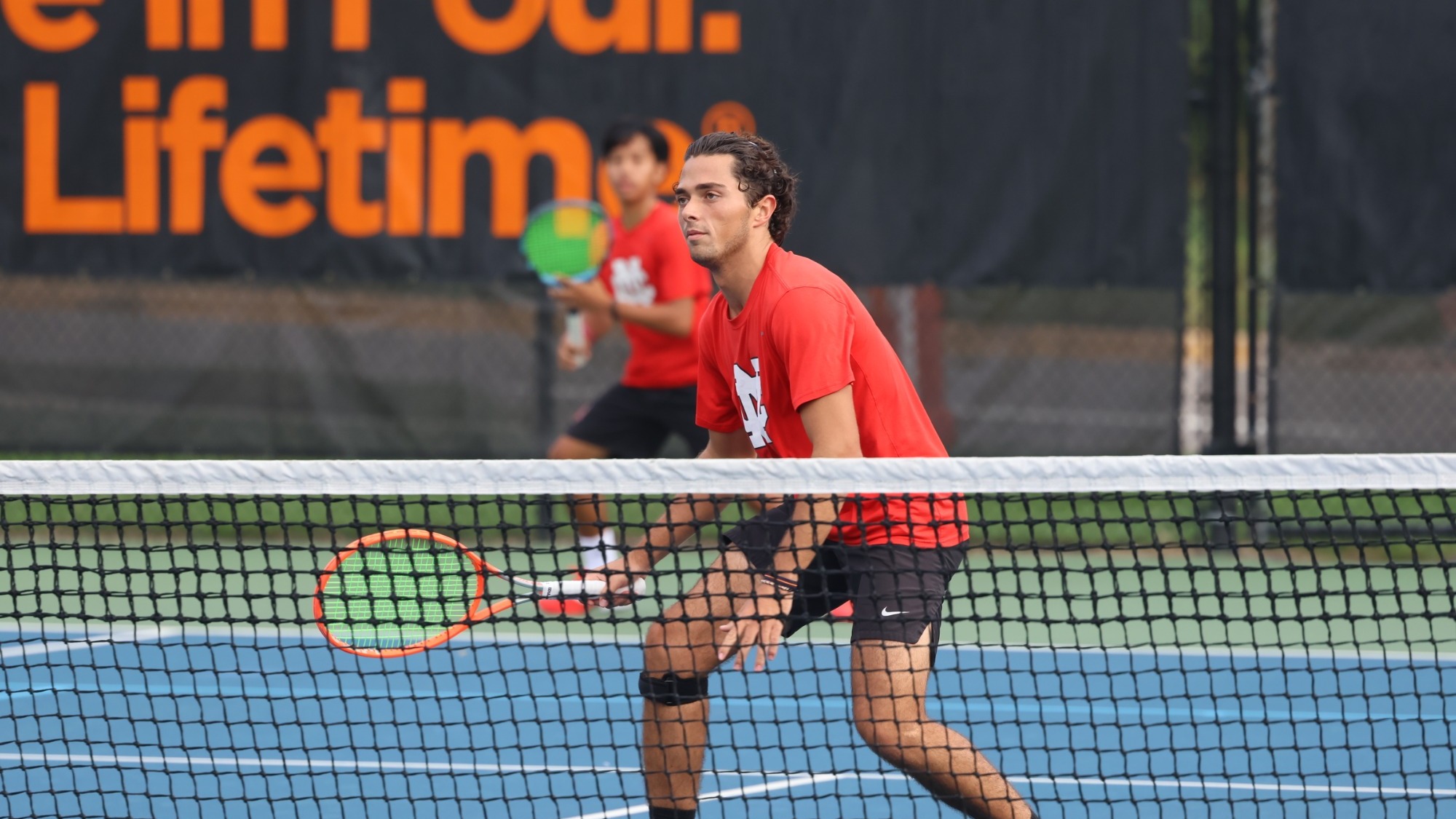 Andres Valverde Gonzalez awaits a return during a doubles match while standing near the net.