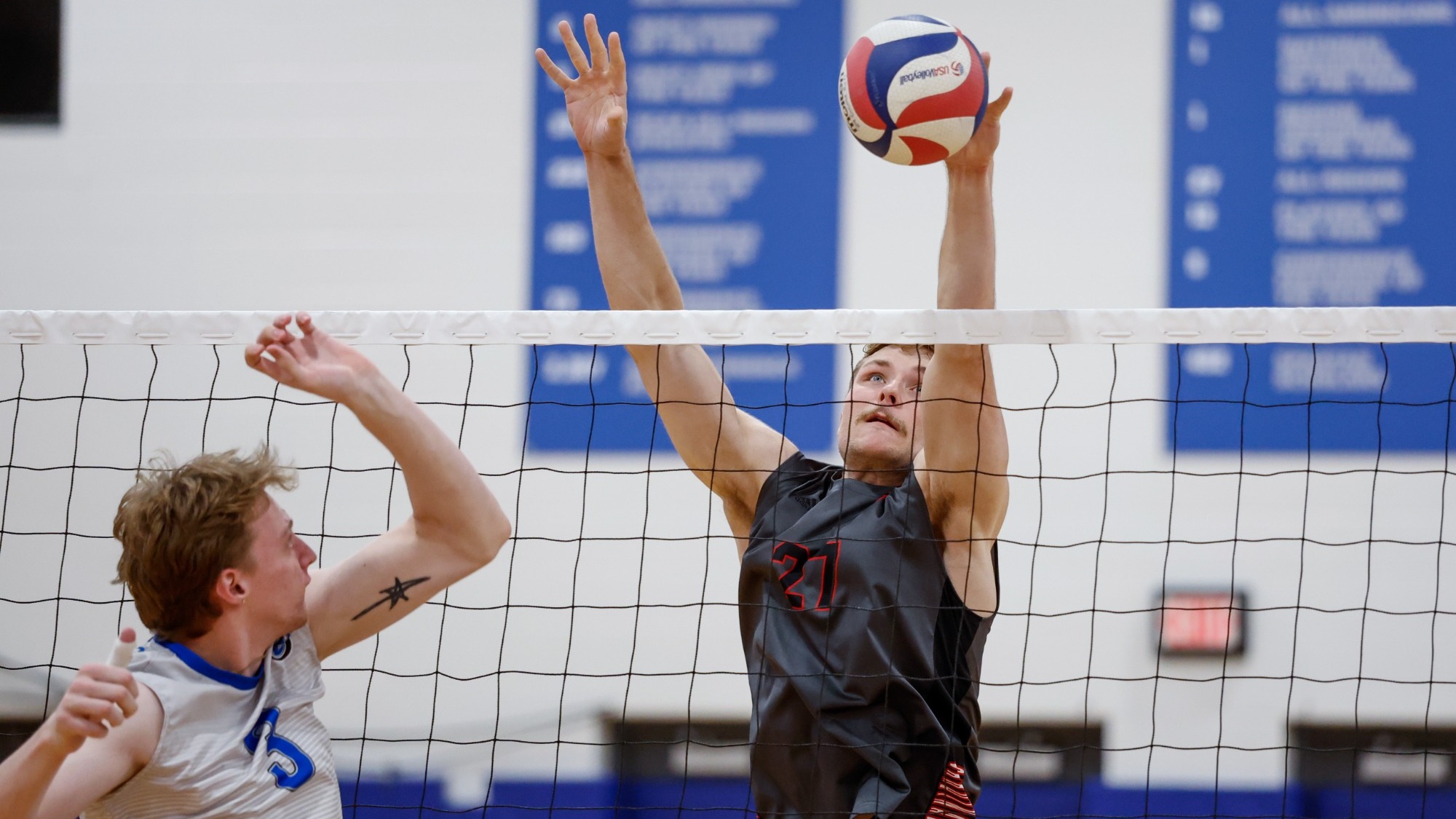 Mitchell Hester deflects the attack of an Aurora University player using his left hand during a volleyball match.