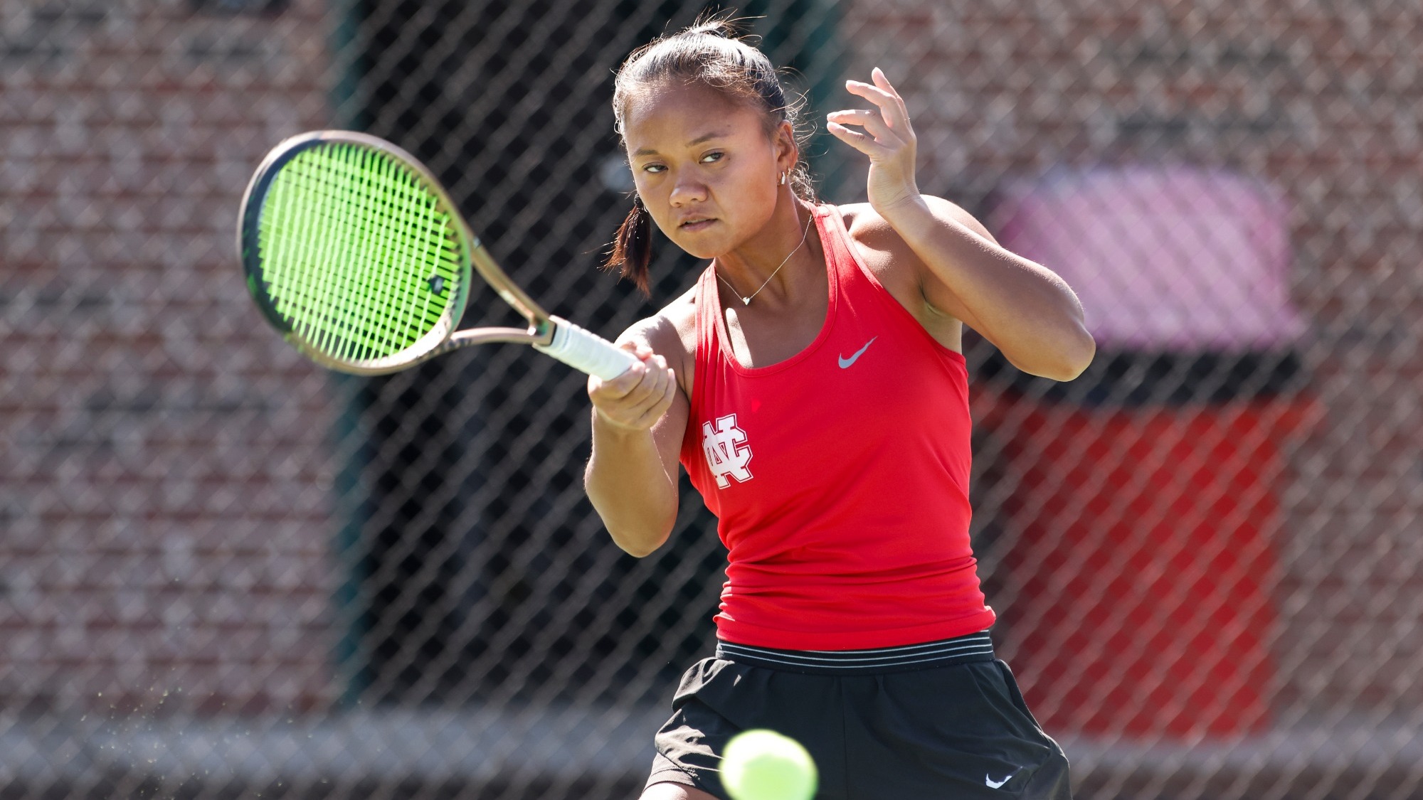 Abigail Penados returns a shot using a forehand swing, focusing intently on the ball. 