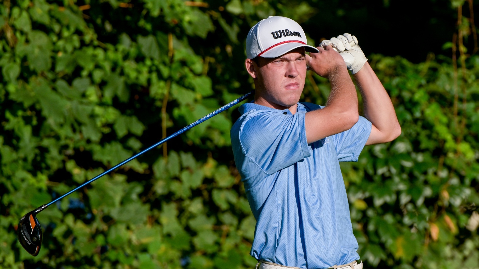 Nicholas Zaimins swings a golf club and is looking at his shot