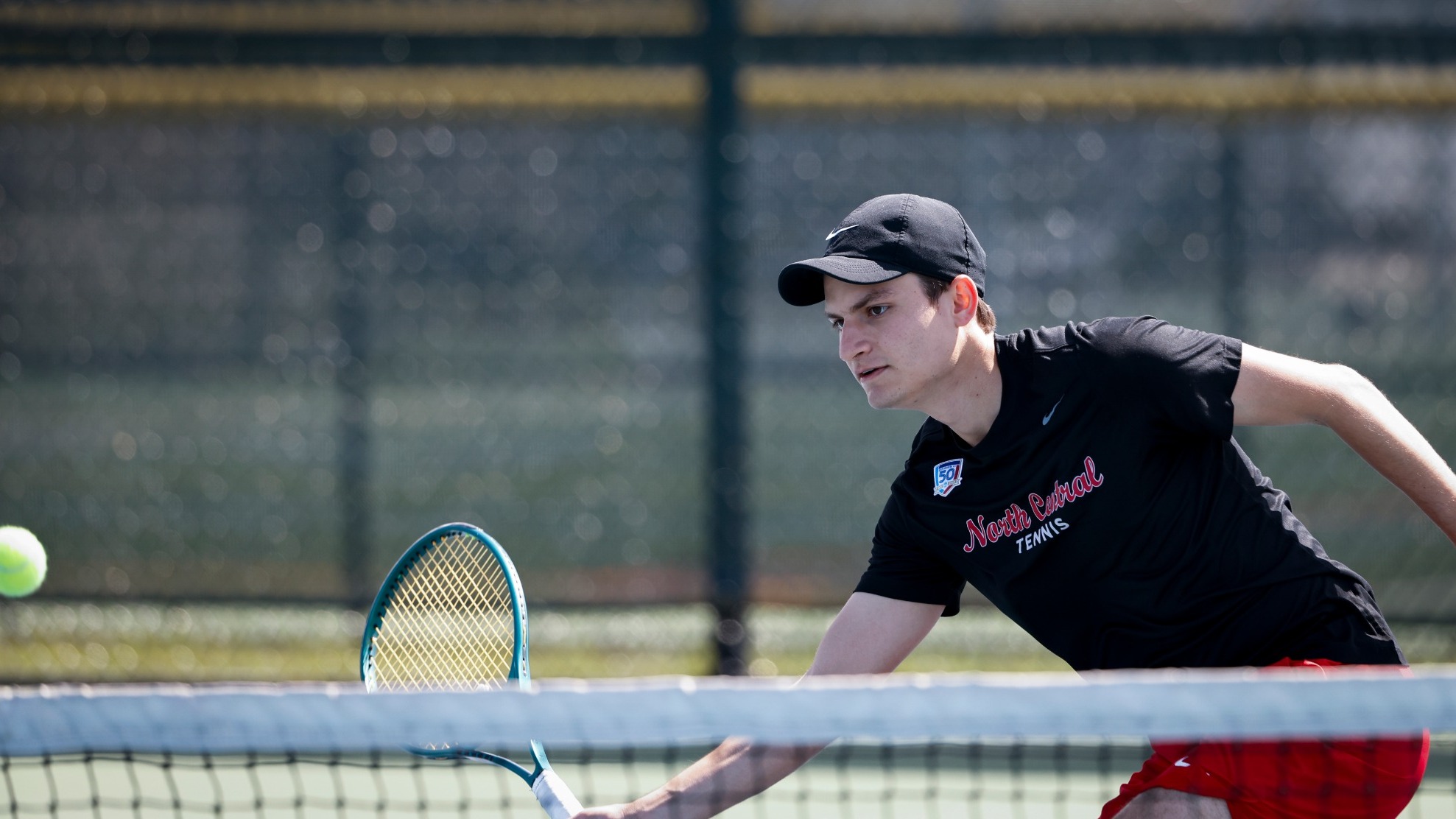 Rafael Lessa volleys a ball just in front of the net using a forehand swing while moving to his right. 