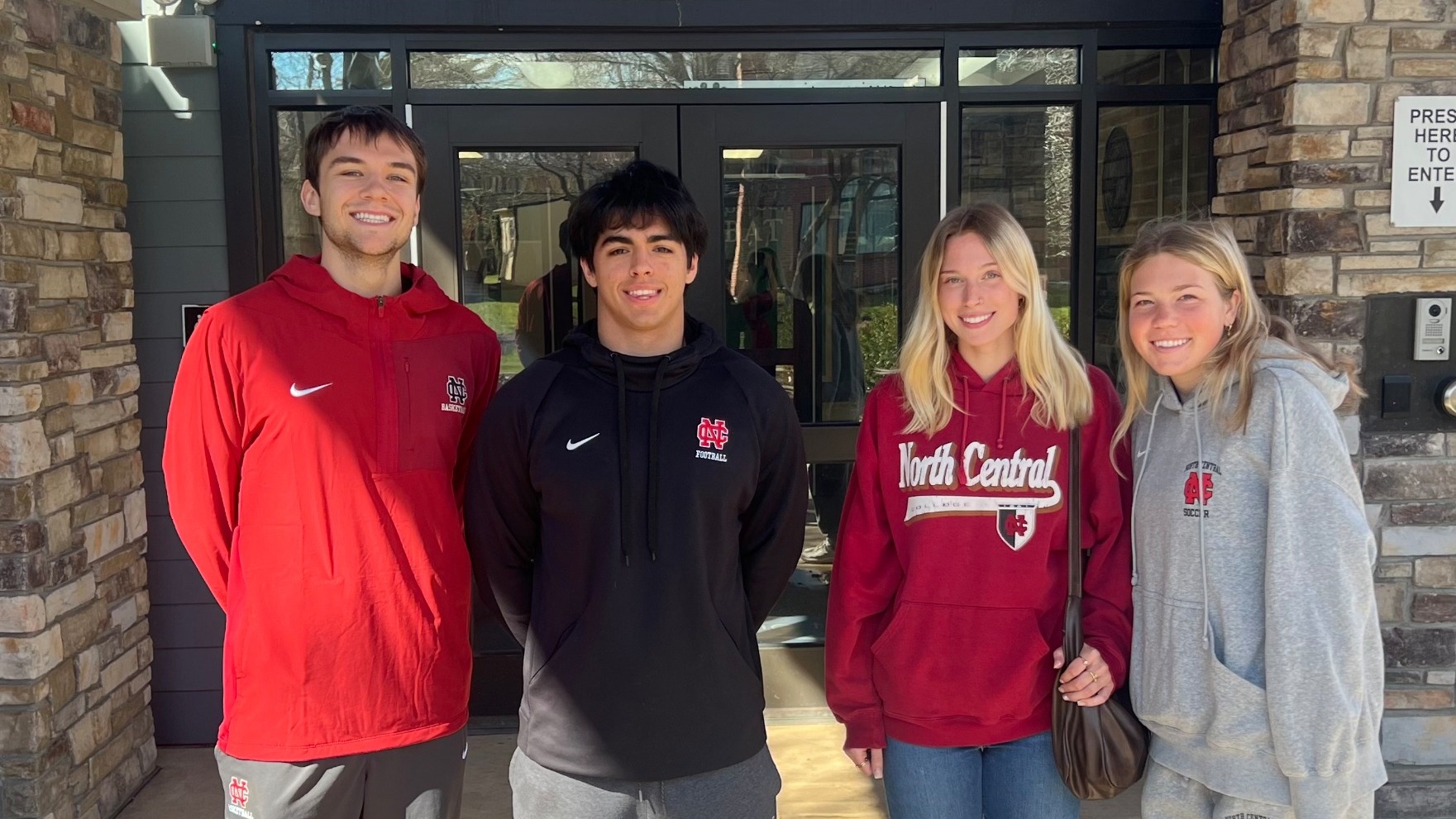 Student-athletes posing in front of Highlands Elementary before reading to first graders