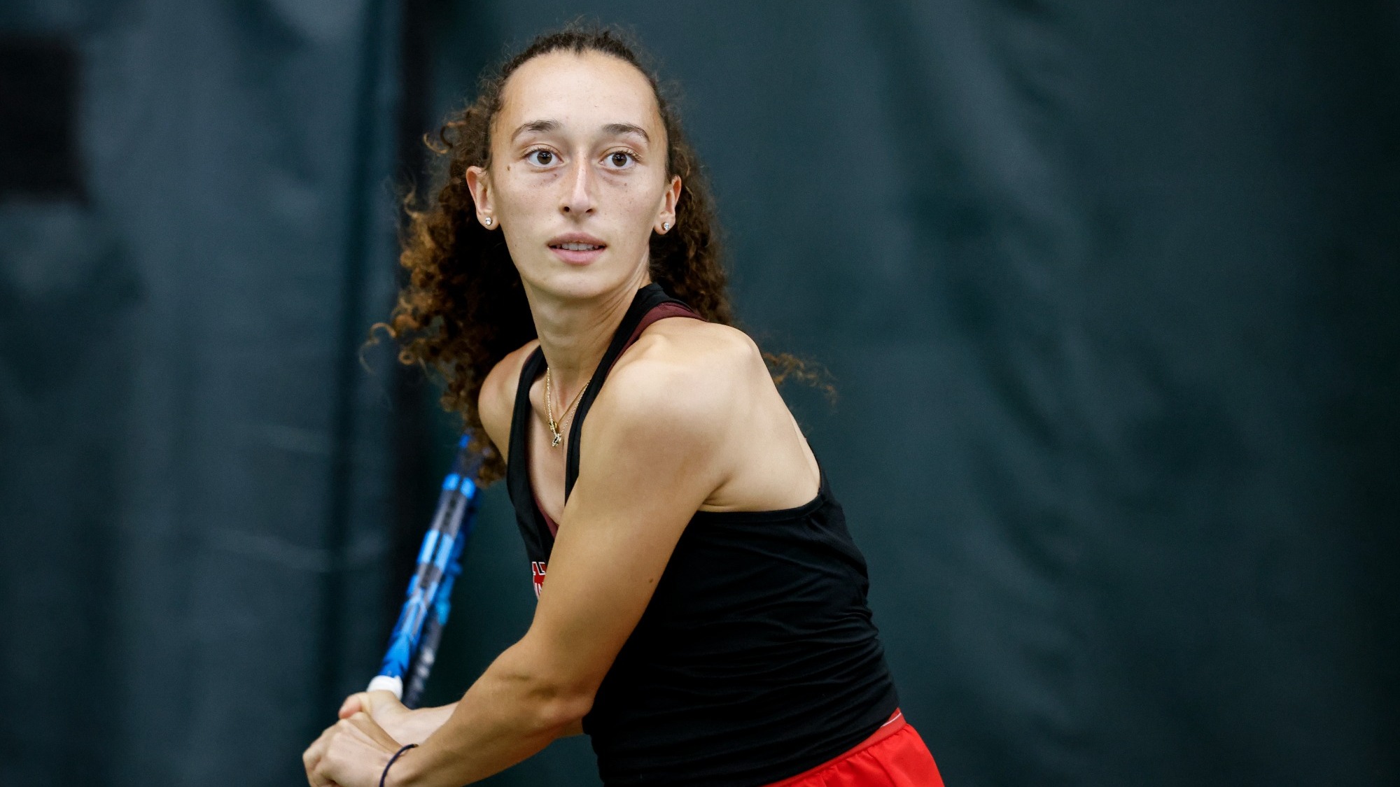 Anais Gerard starts her backhanded backswing as a ball approaches during a tennis match