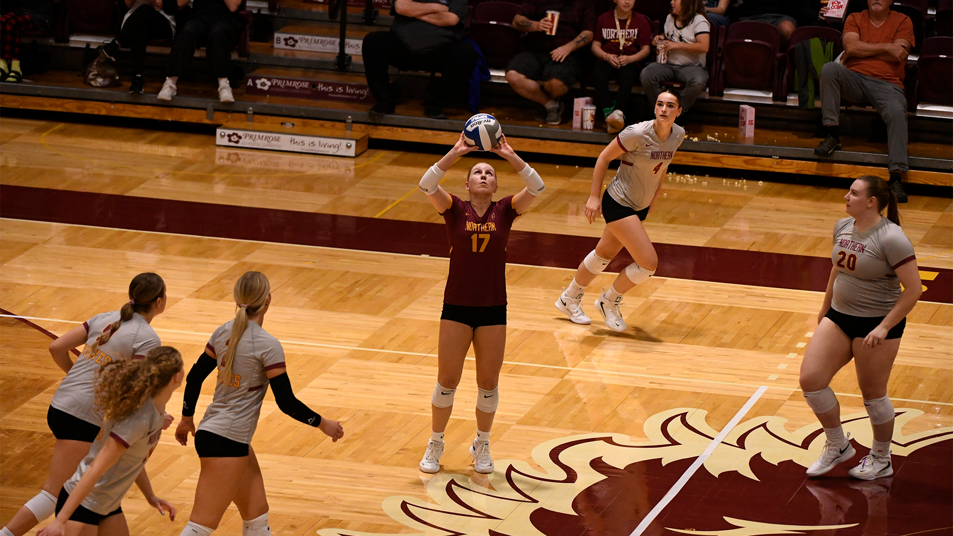 10.21 Volleyball Preview - Ashley Yost sets the ball in the middle of the court while her teammates watch in ready