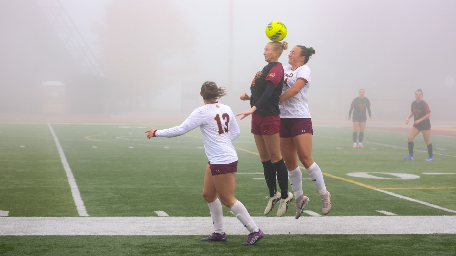 NSU's Lauren Carpenter jumps up for a header, sandwiched by two UMD defenders in the Wolves' loss to the Bulldogs, 1-0.