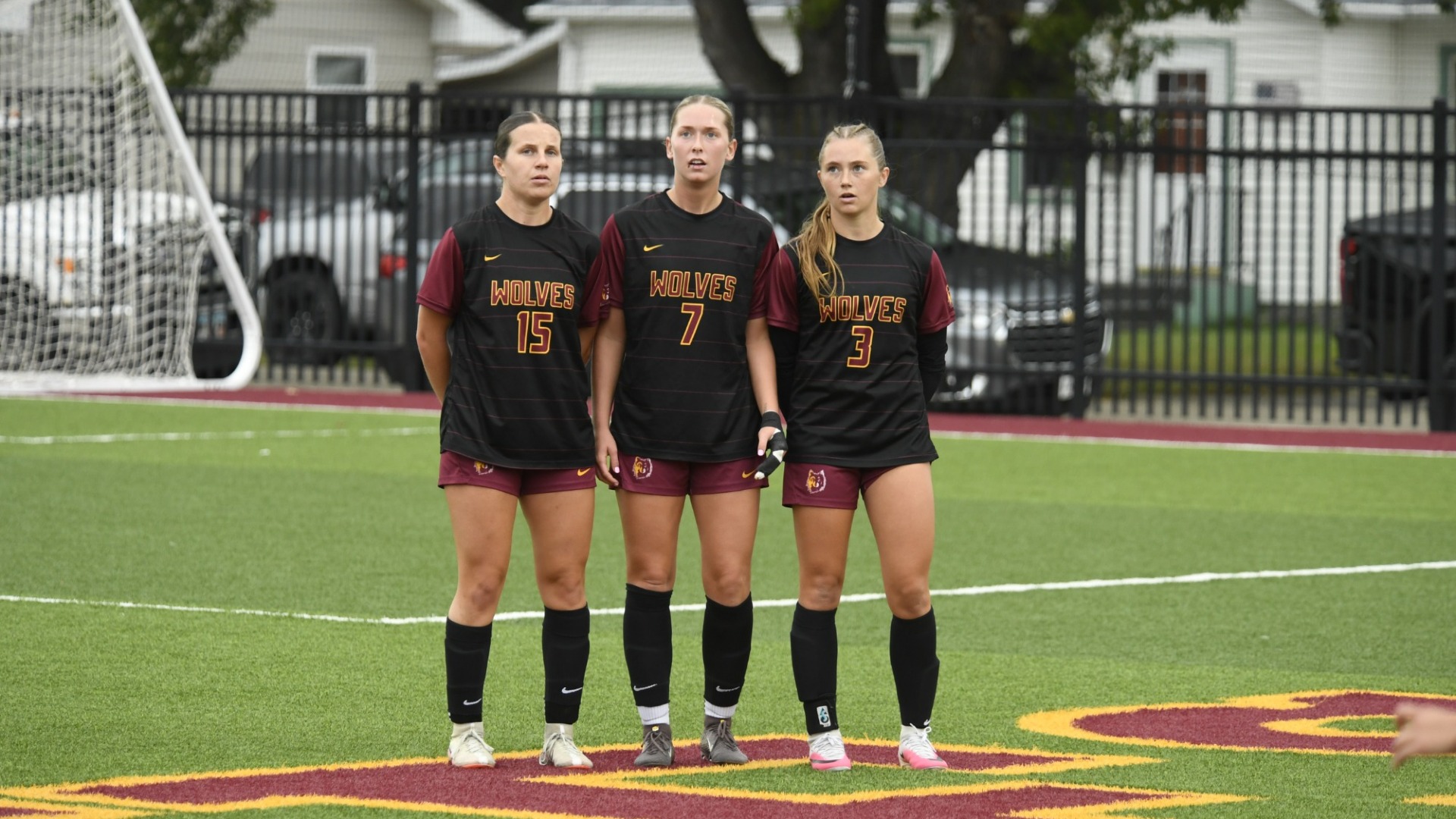 Kylie Albert, Jaylee Hofer, and Chloe Voss line up to block a free kick deep in their own territory.