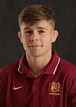 Headshot for Wyatt Turnquist in a maroon polo with a gray background. 