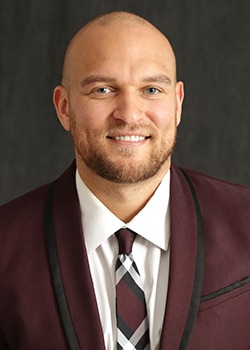 Headshot for Terrell Newton, wearing a maroon jacket, with white shirt, and a patterned tie