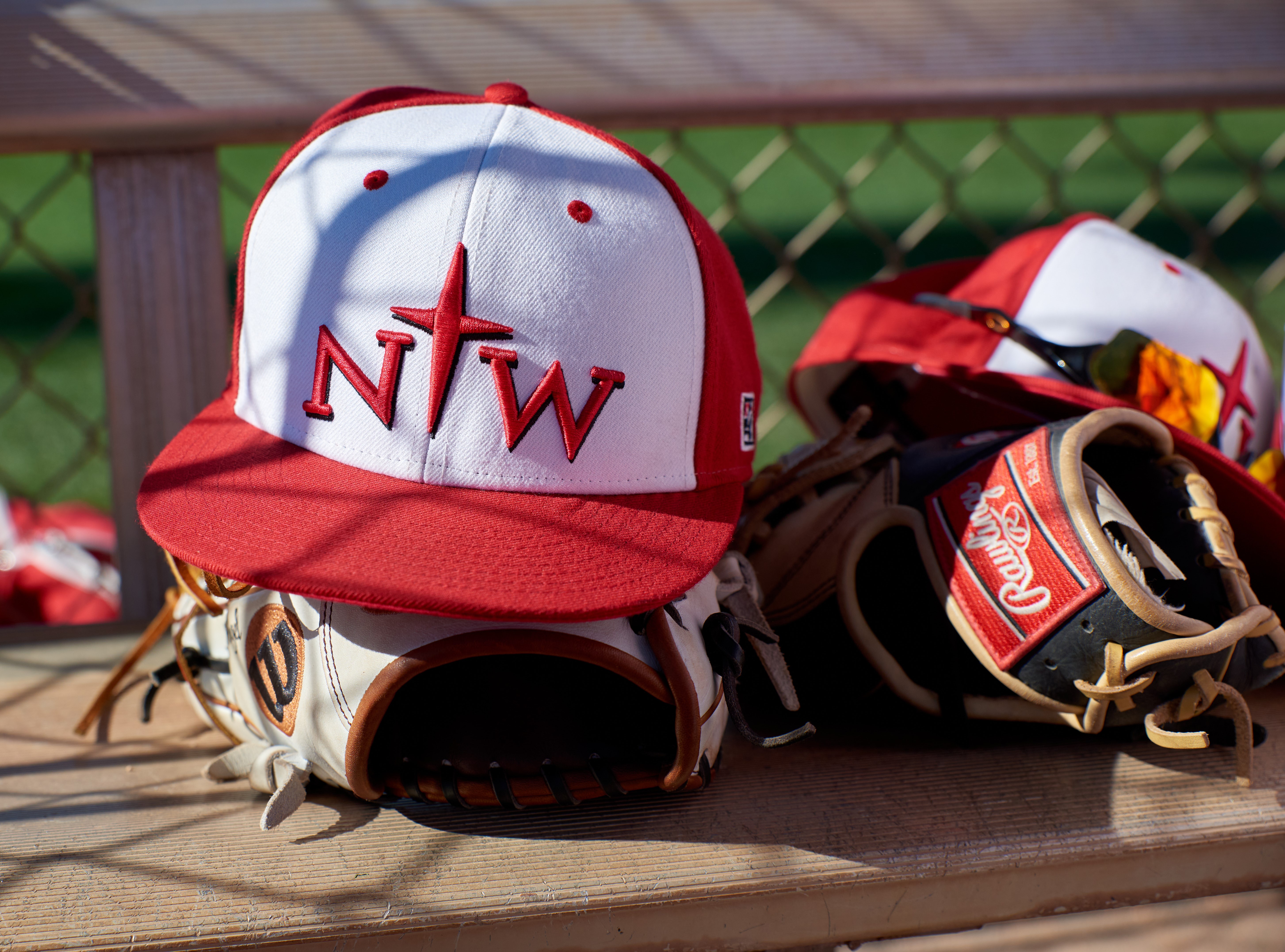 A Northwestern College Red Raiders baseball hat rests on a glove during a game against the Presentation College Saints at Kino Sports Complex on March 7, 2020 in Tucson, Arizona. (Zachary Lucy Photography)