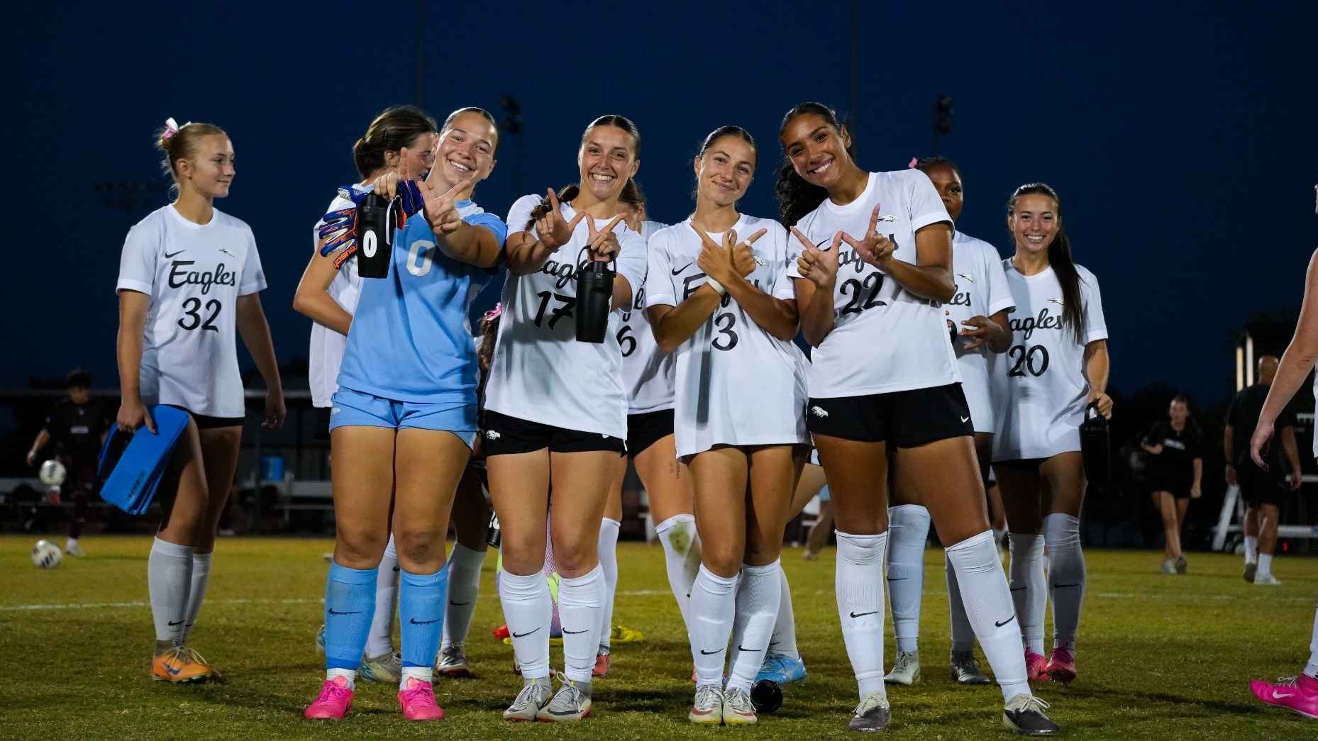 Oklahoma Christian women’s soccer players sOklahoma Christian women’s soccer players smile and make “W” signs with their hands on the field after beating UT Dallas.mile and make “W” signs with their hands on the field after beating UT Dallas.