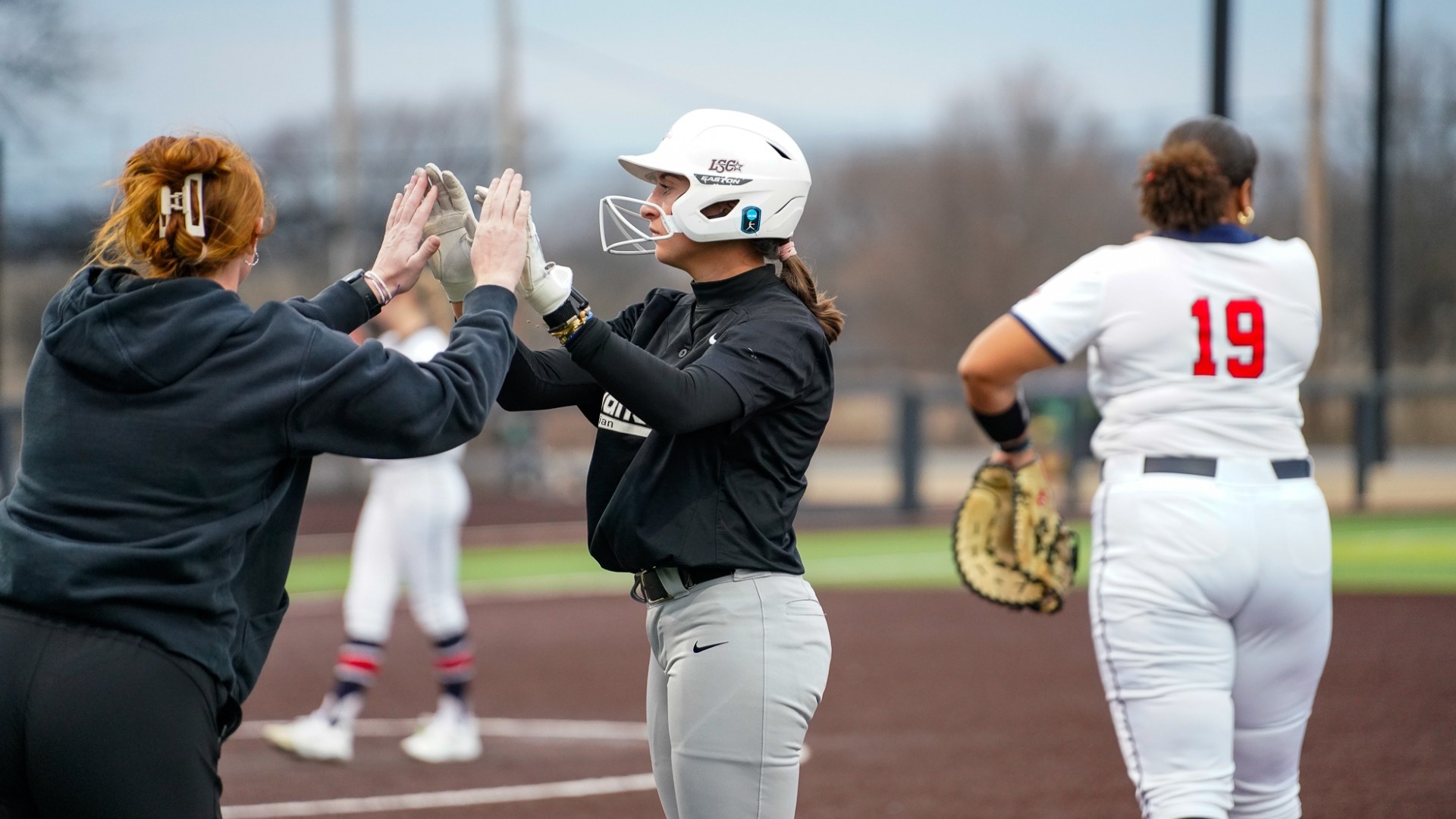 Kadence Brewster high-fiving 1st-base coach